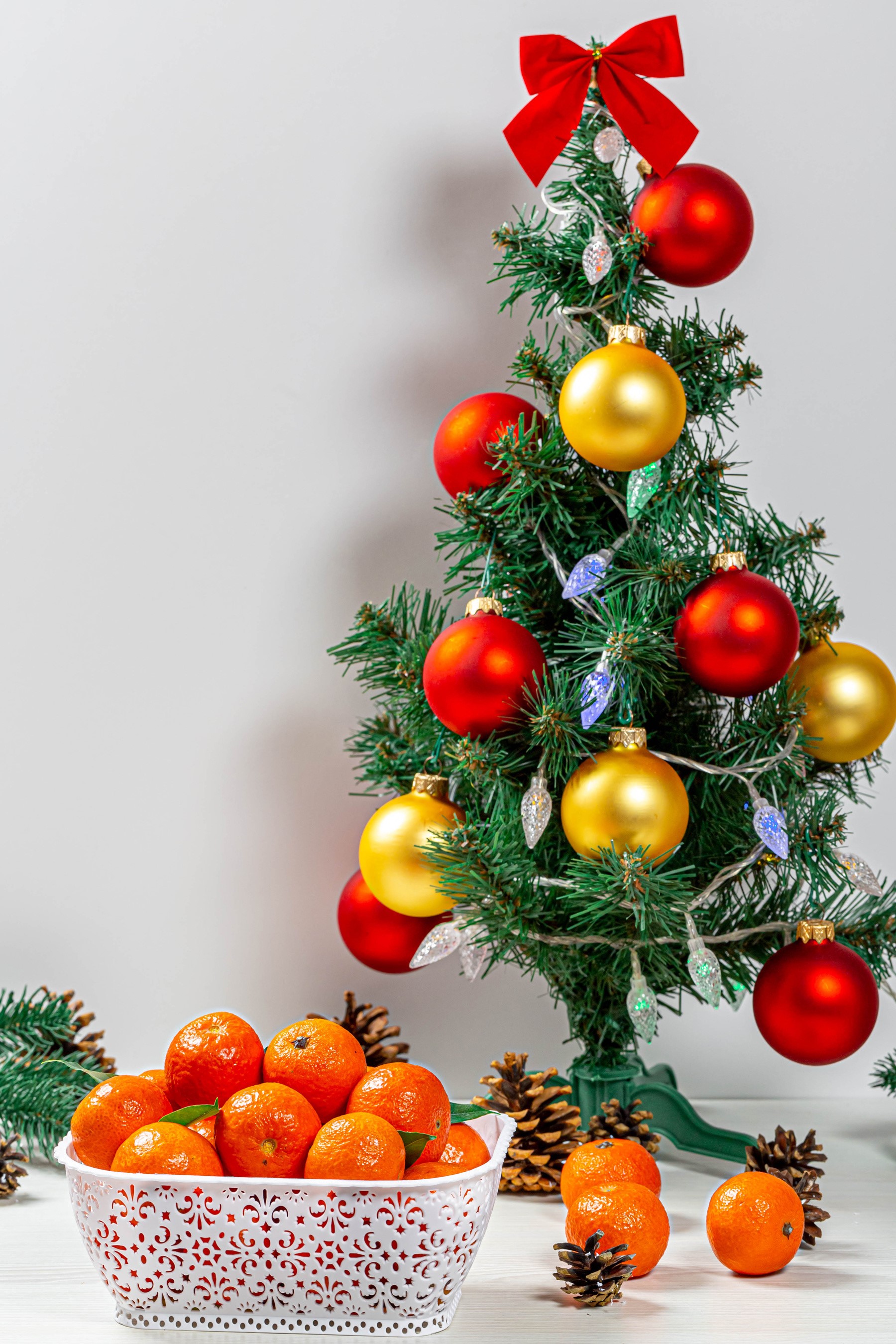 Christmas tree with ornaments and mandarins in a bowl HD Phone Wallpaper