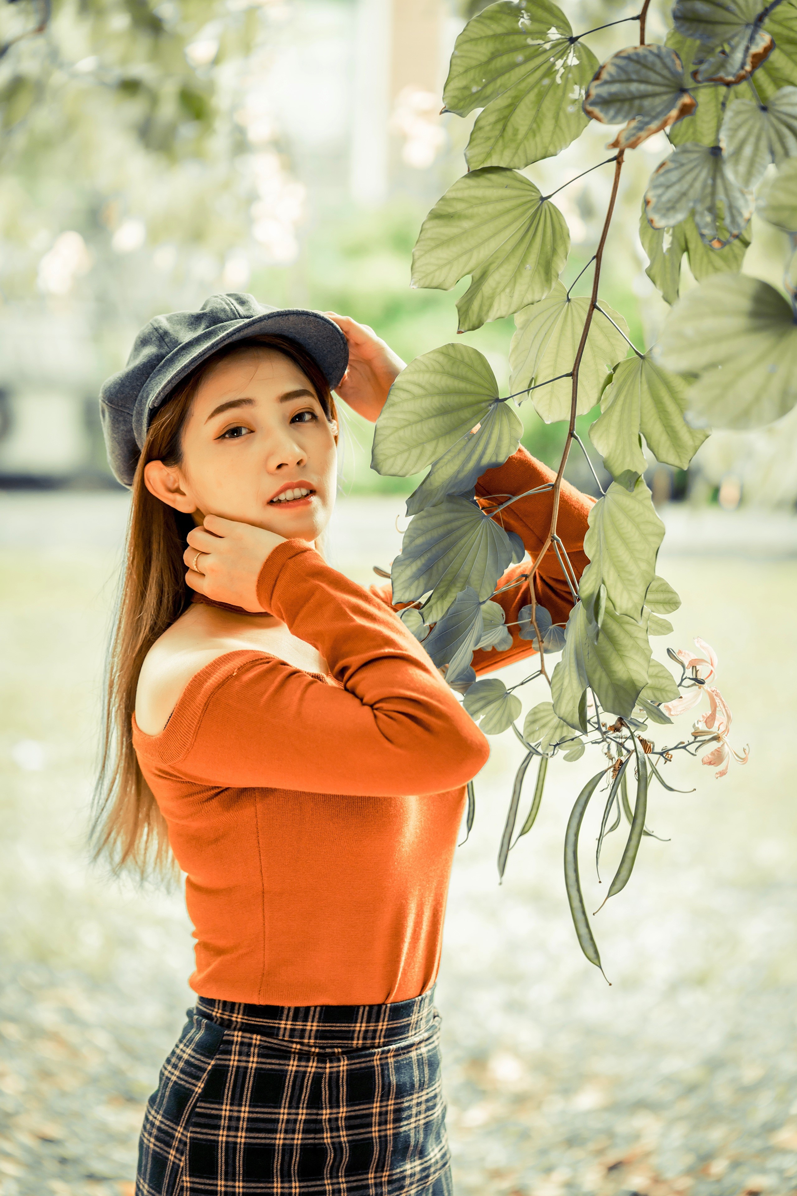 Asian woman in a hat and orange top with plaid skirt HD Phone Wallpaper