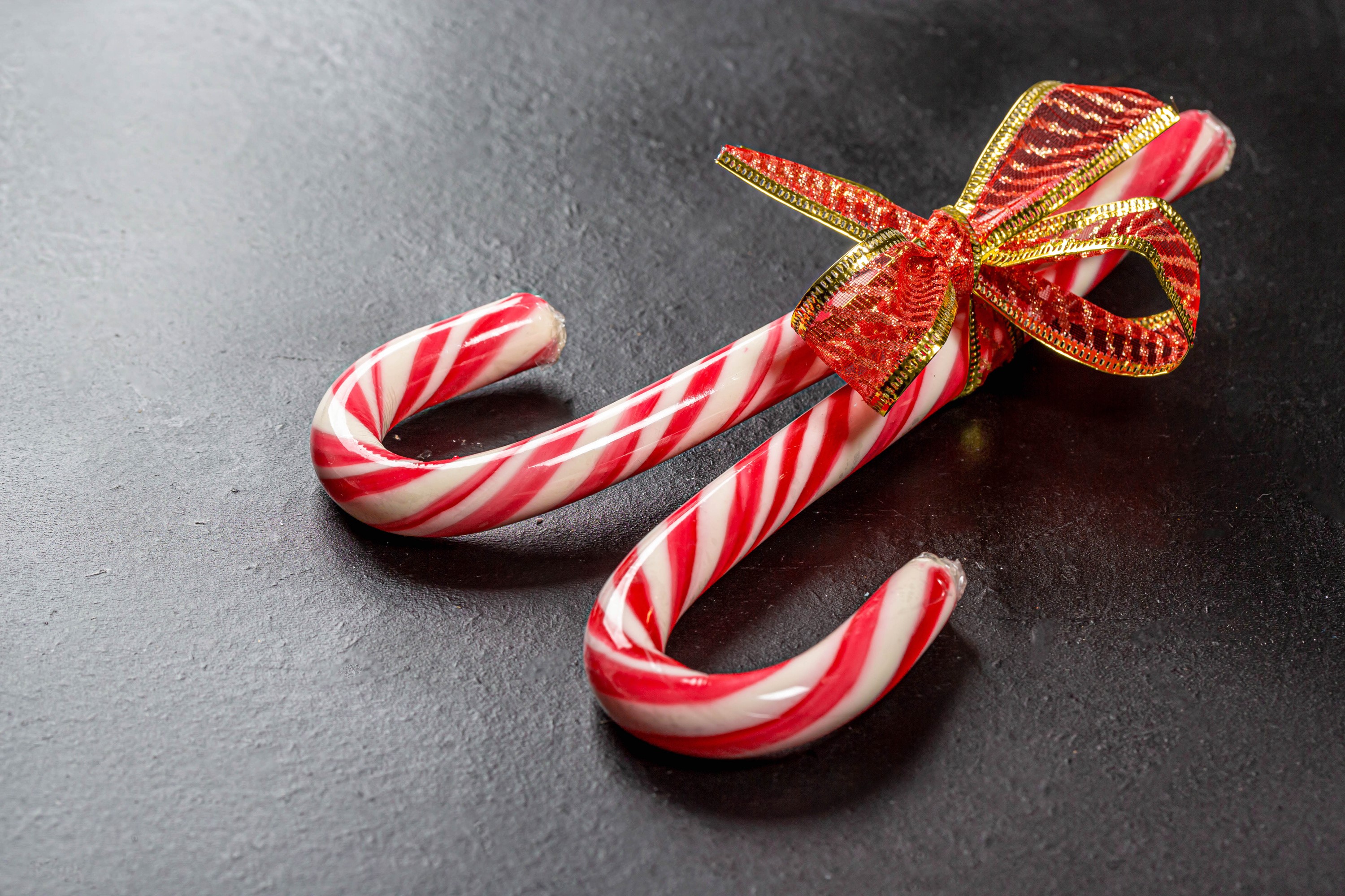 Two candy canes tied with a red and gold bow HD Wallpaper