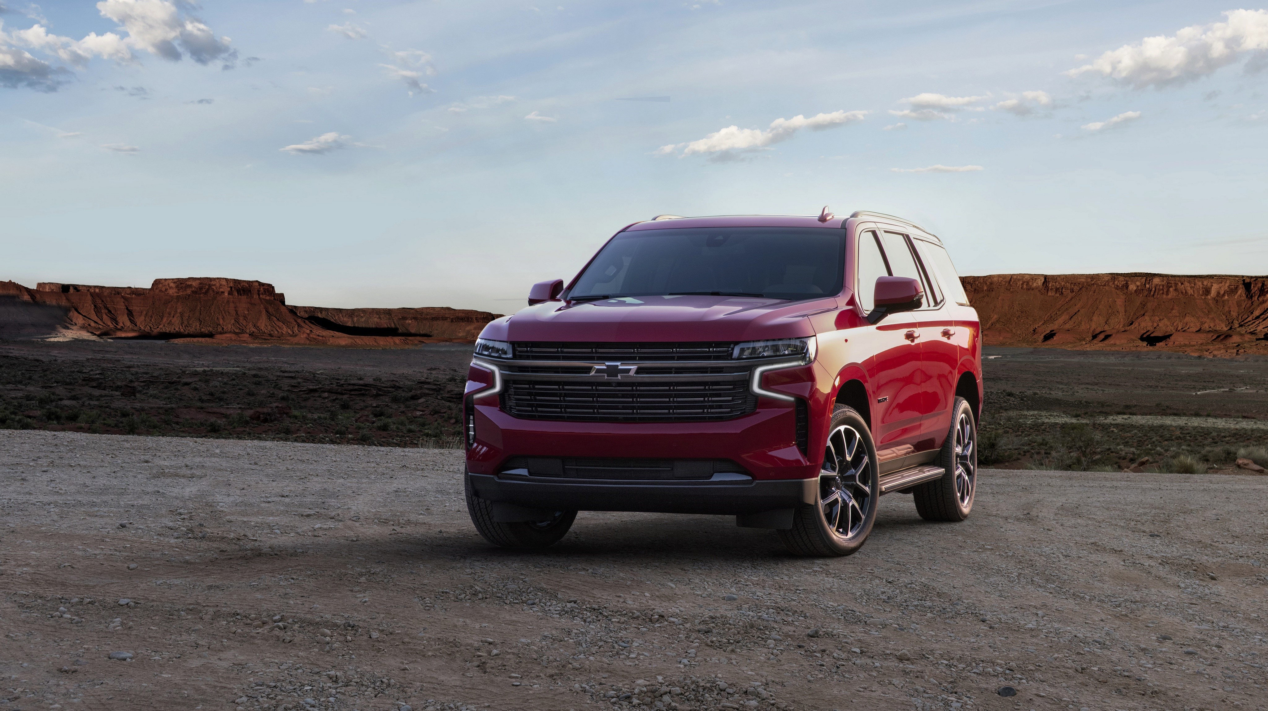Red Chevrolet Tahoe SUV in a desert landscape HD Wallpaper