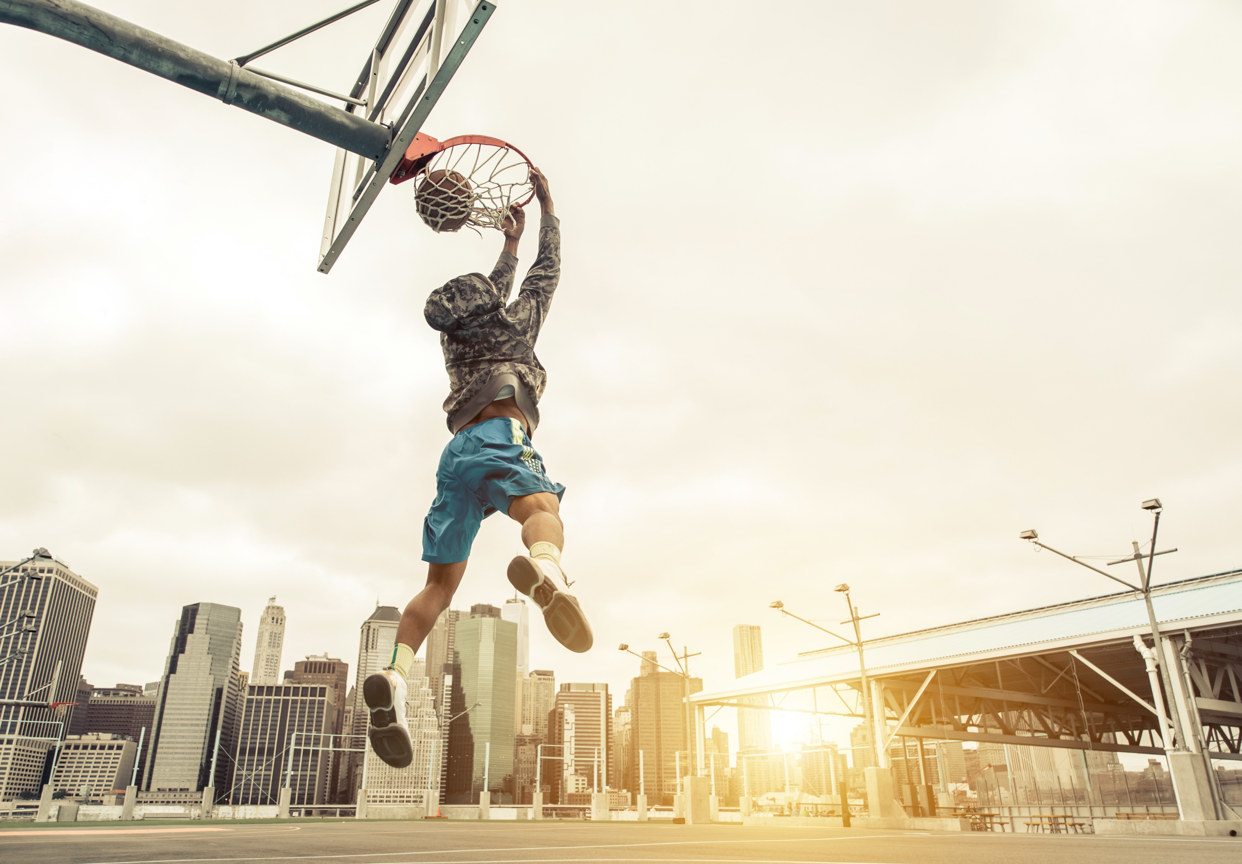 Man dunking a basketball in a city HD Wallpaper