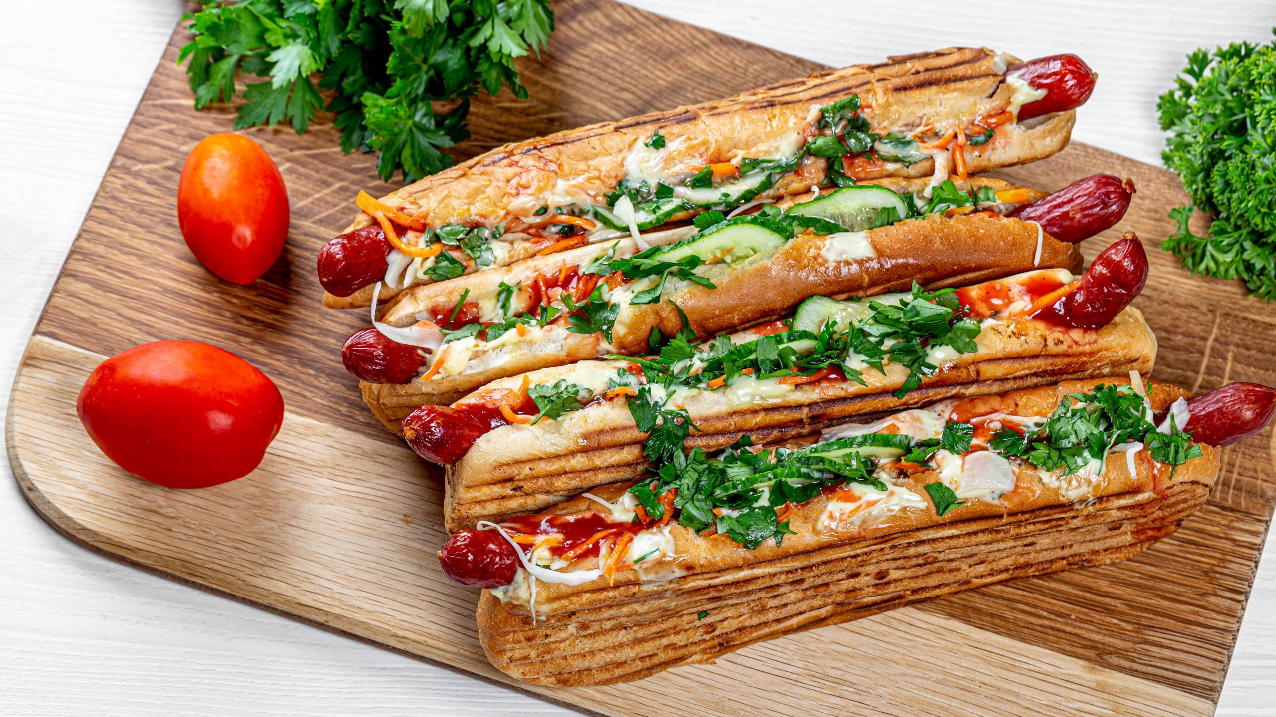 Four hot dogs with toppings on a wooden board HD Wallpaper