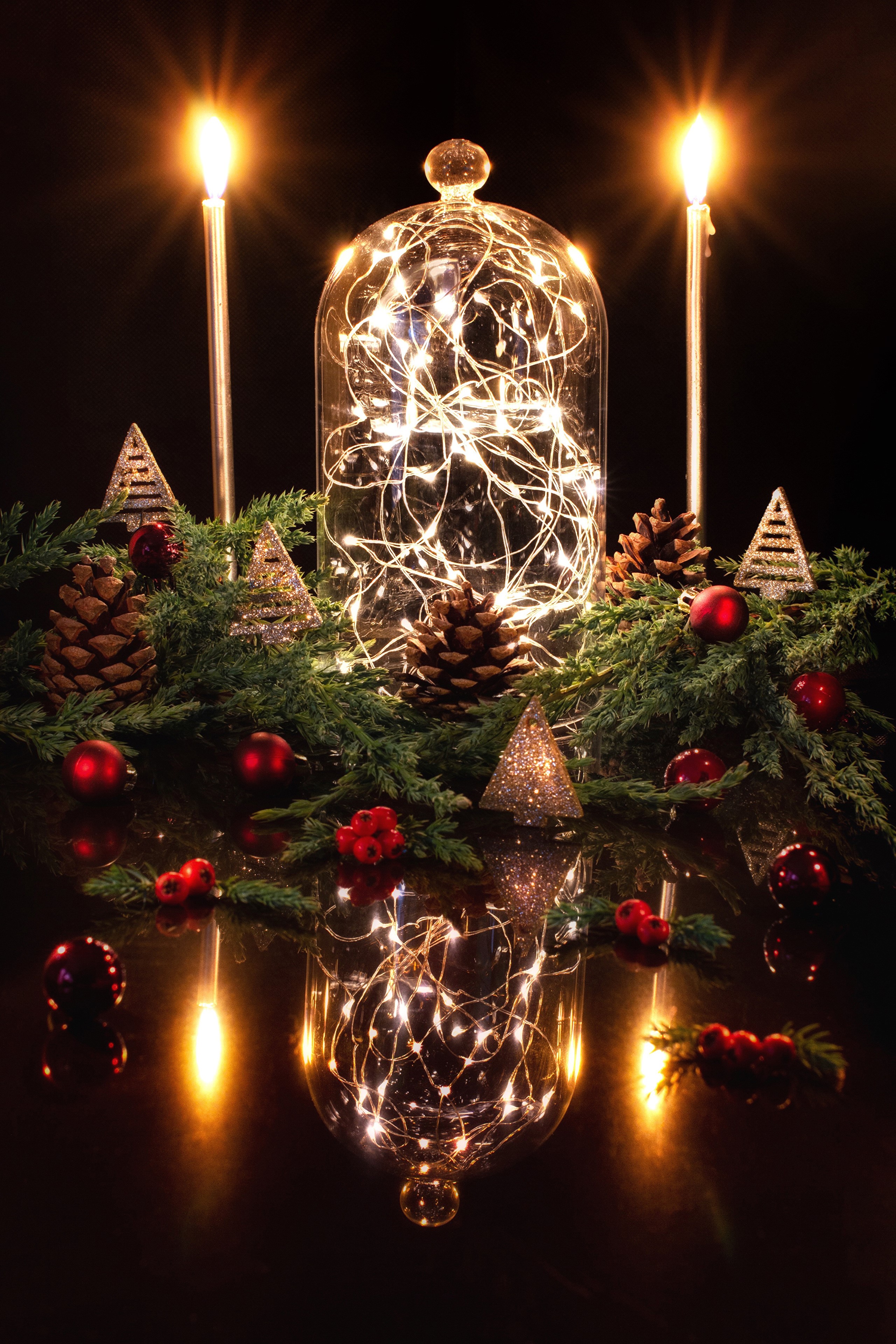 Christmas lights in a glass dome with candles and pine cones HD Phone Wallpaper
