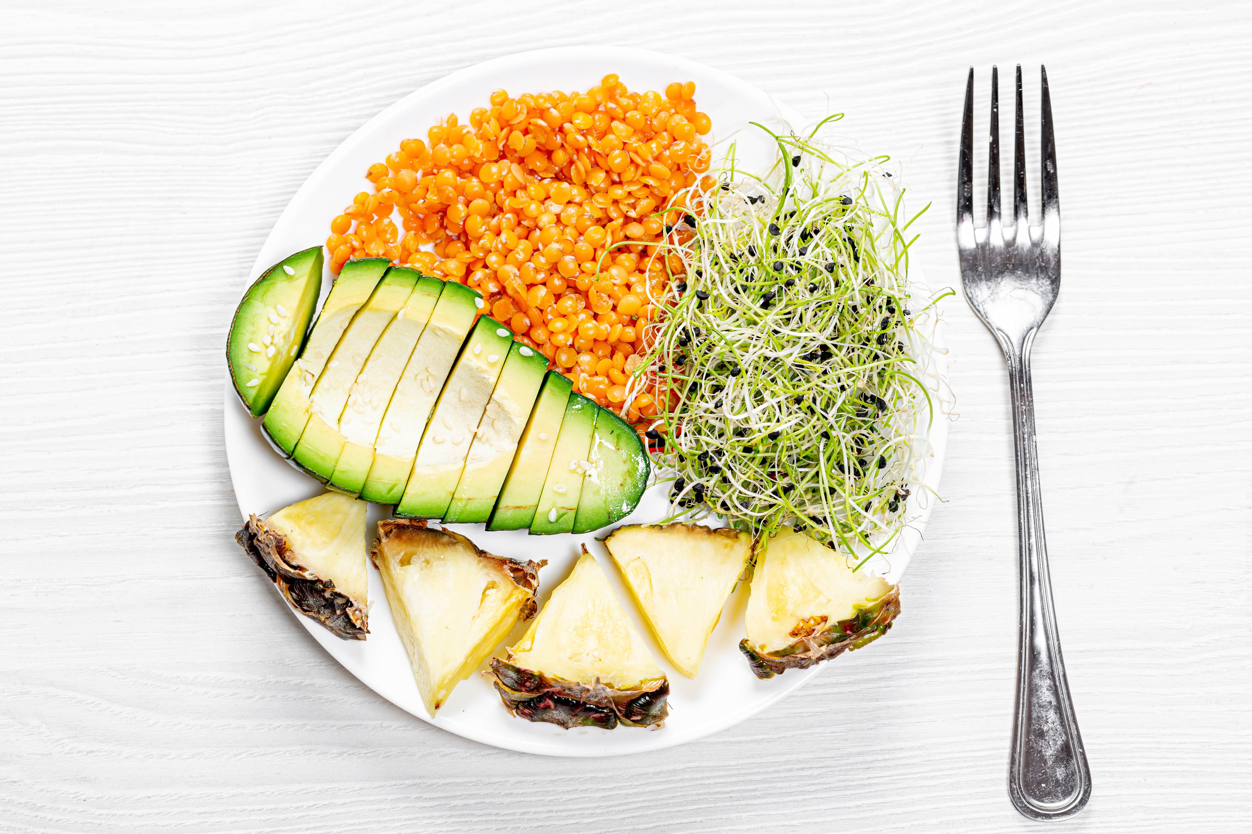 Plate of lentils, avocado, sprouts, and pineapple with fork HD Wallpaper