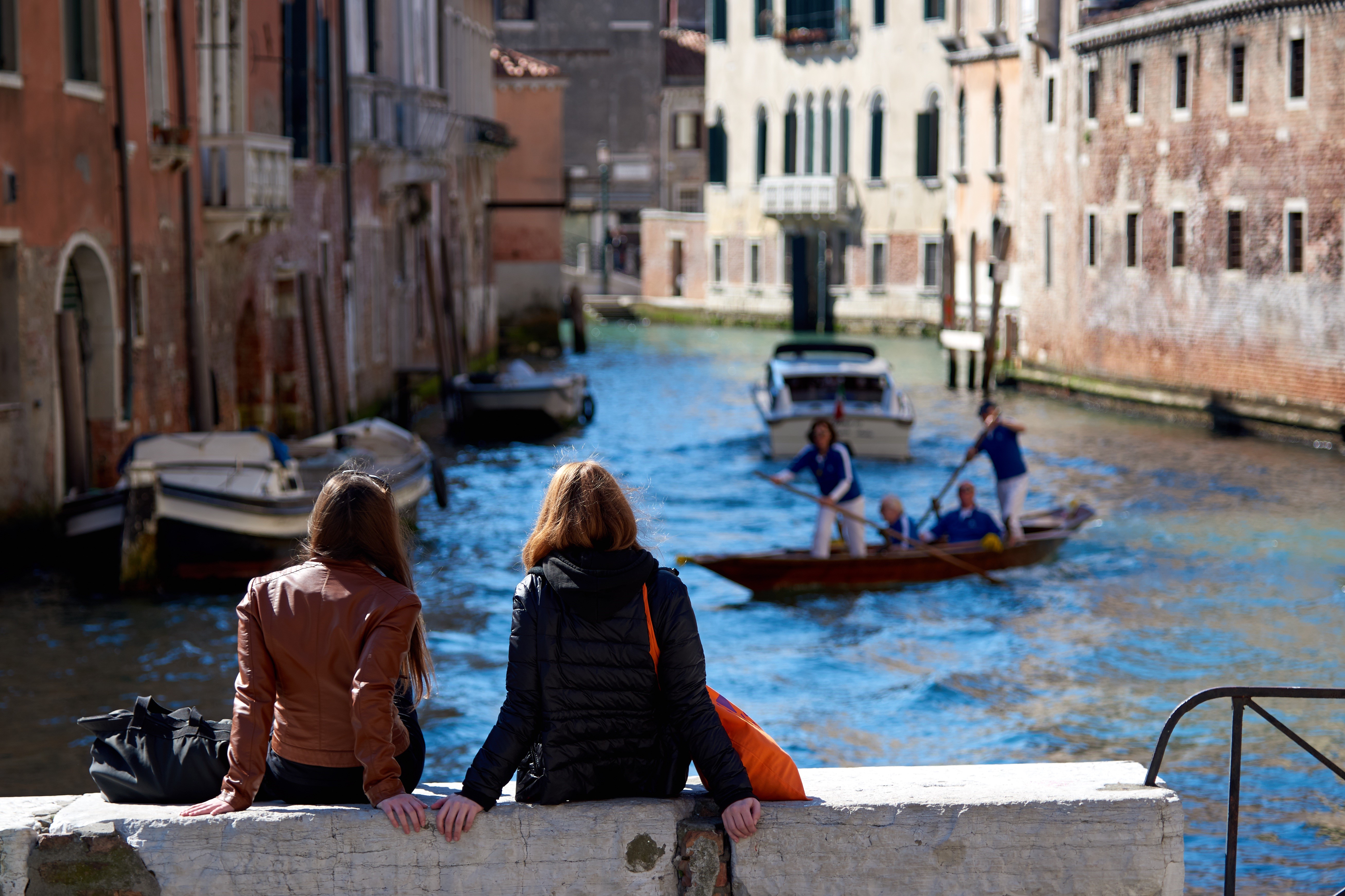Two women sitting by a canal in Venice, Italy HD Wallpaper