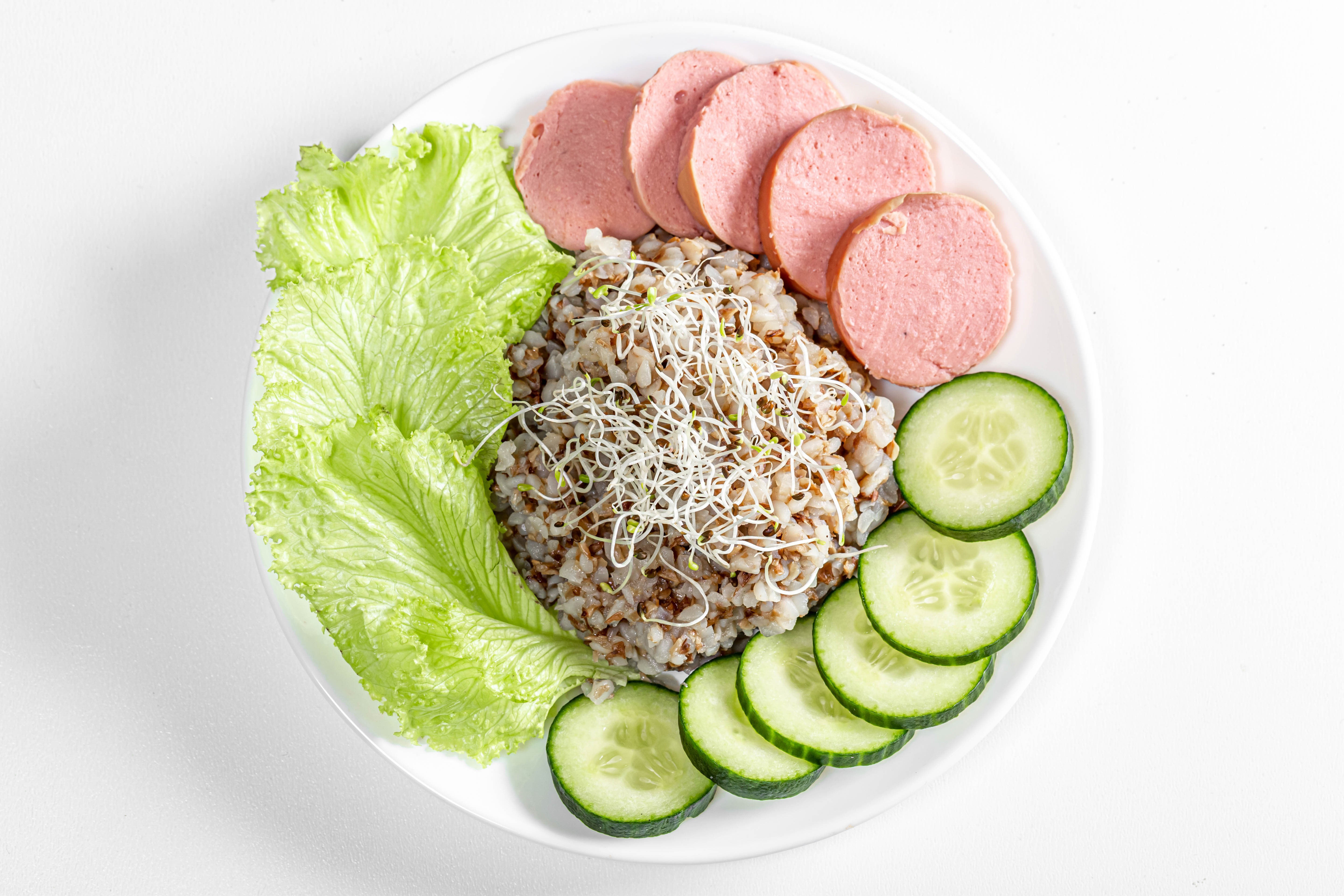 Buckwheat porridge with sausage, lettuce, and cucumber on a plate HD Wallpaper