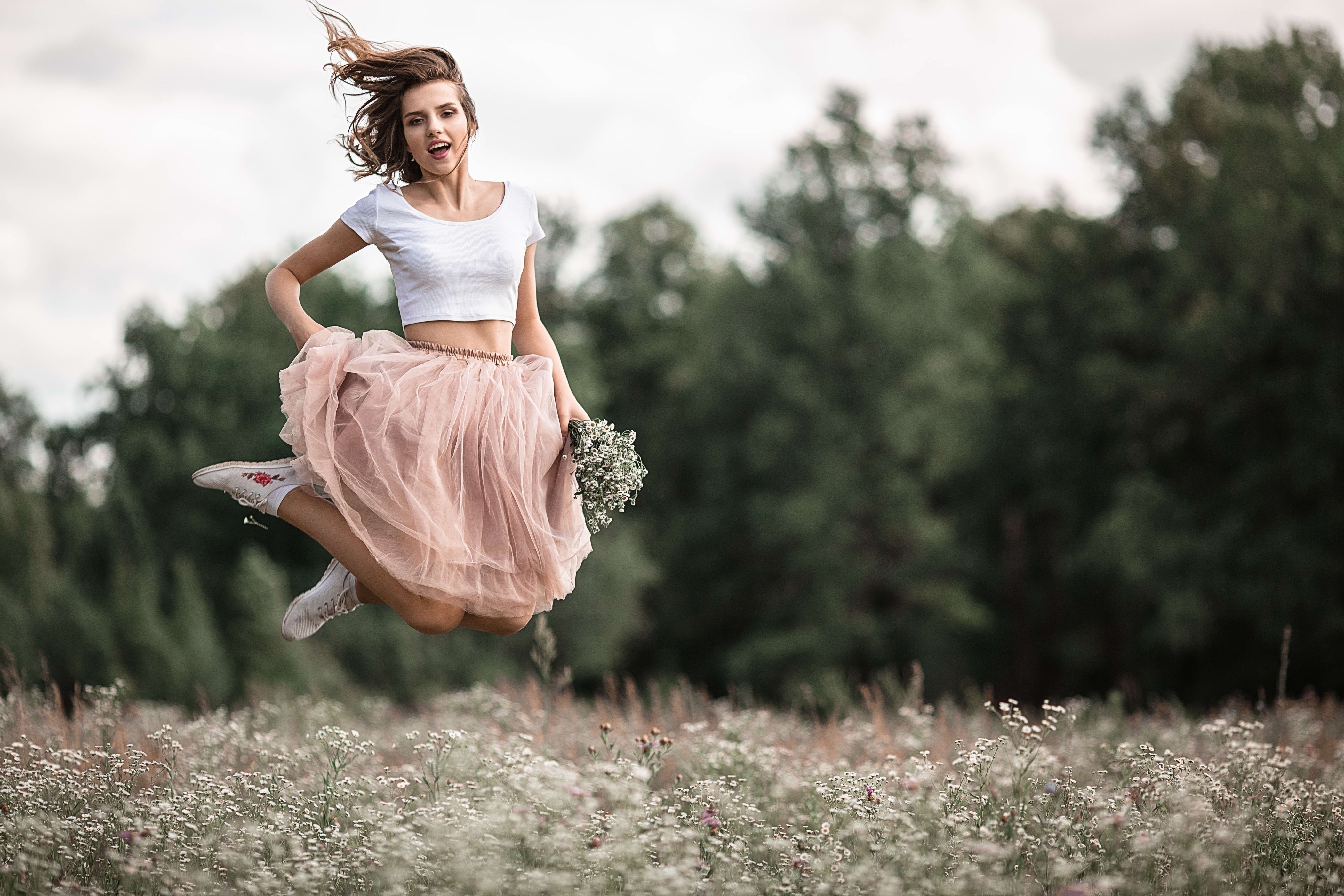 Woman in pink skirt jumping in field HD Wallpaper