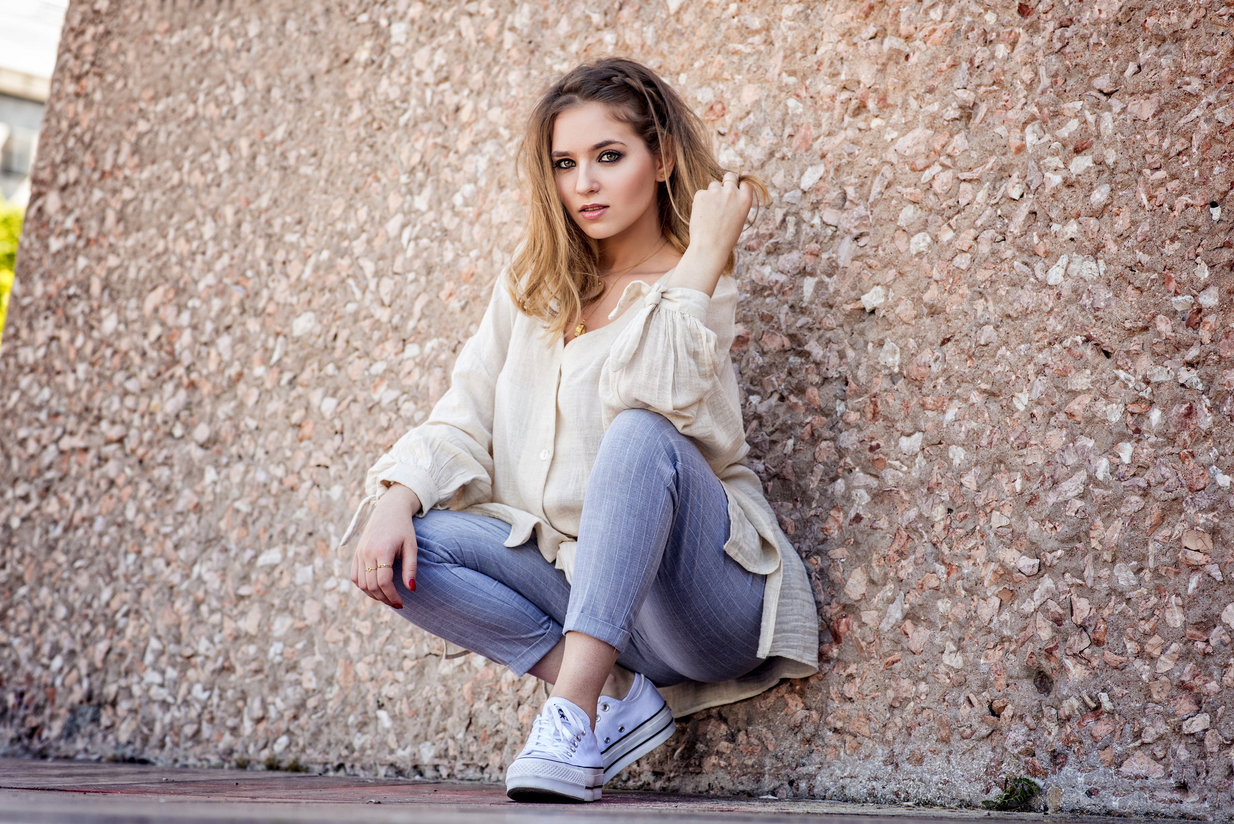 Woman in casual clothes squatting against a wall HD Wallpaper