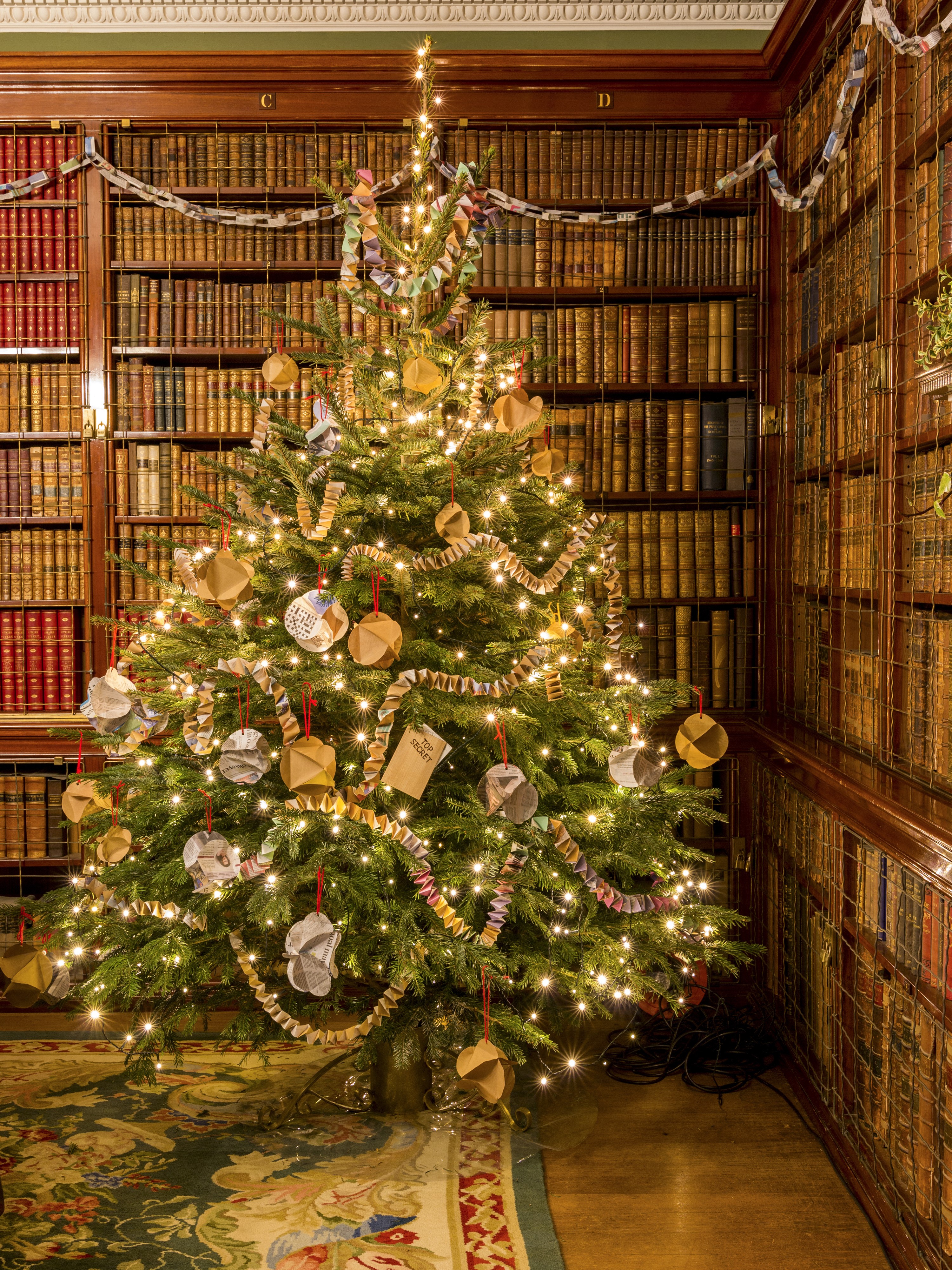 Christmas tree decorated with lights and ornaments in a library HD Phone Wallpaper