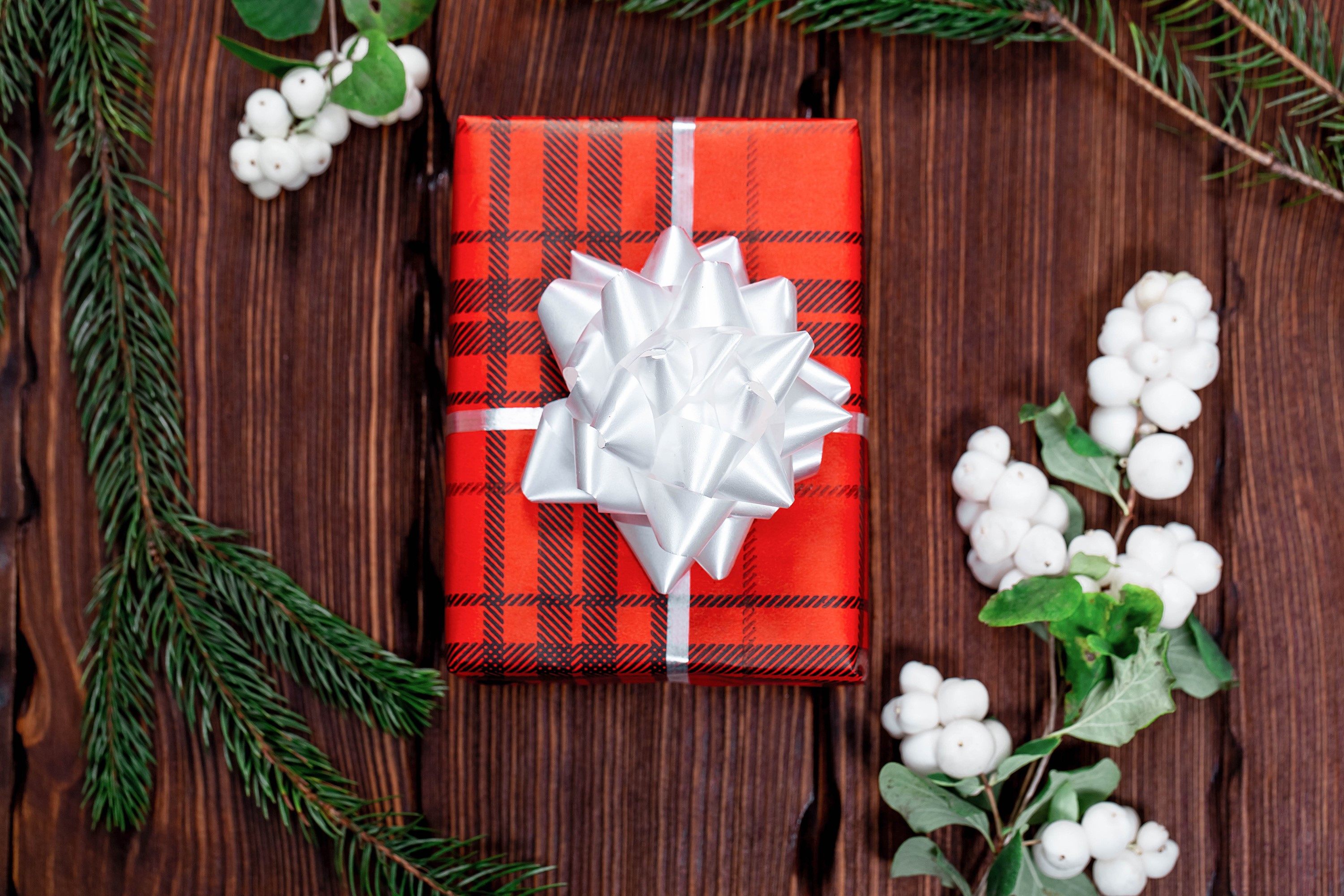 Christmas gift with pine branches and white berries on wood HD Wallpaper