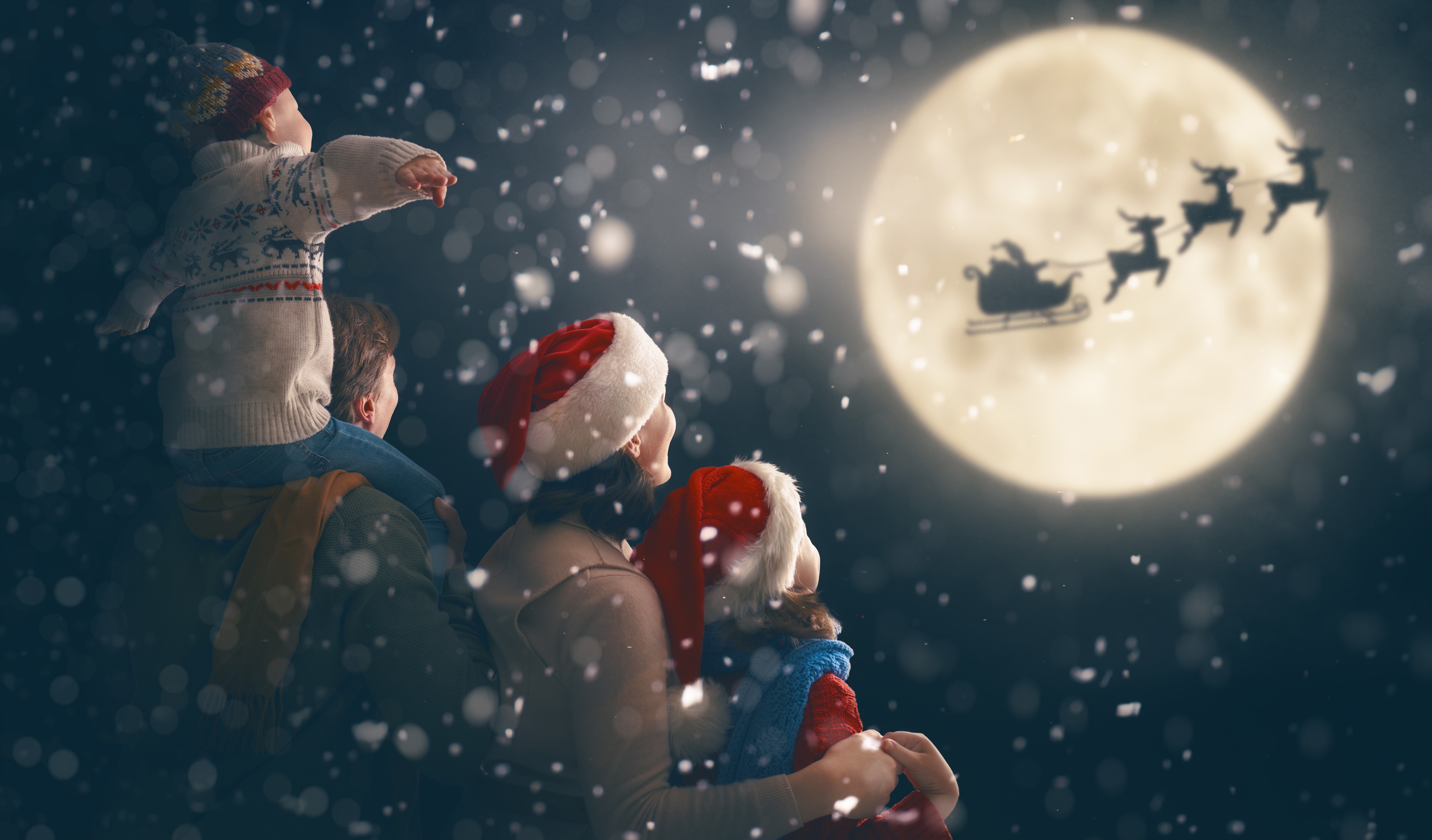 Family watches Santa's sleigh fly across the moon HD Wallpaper