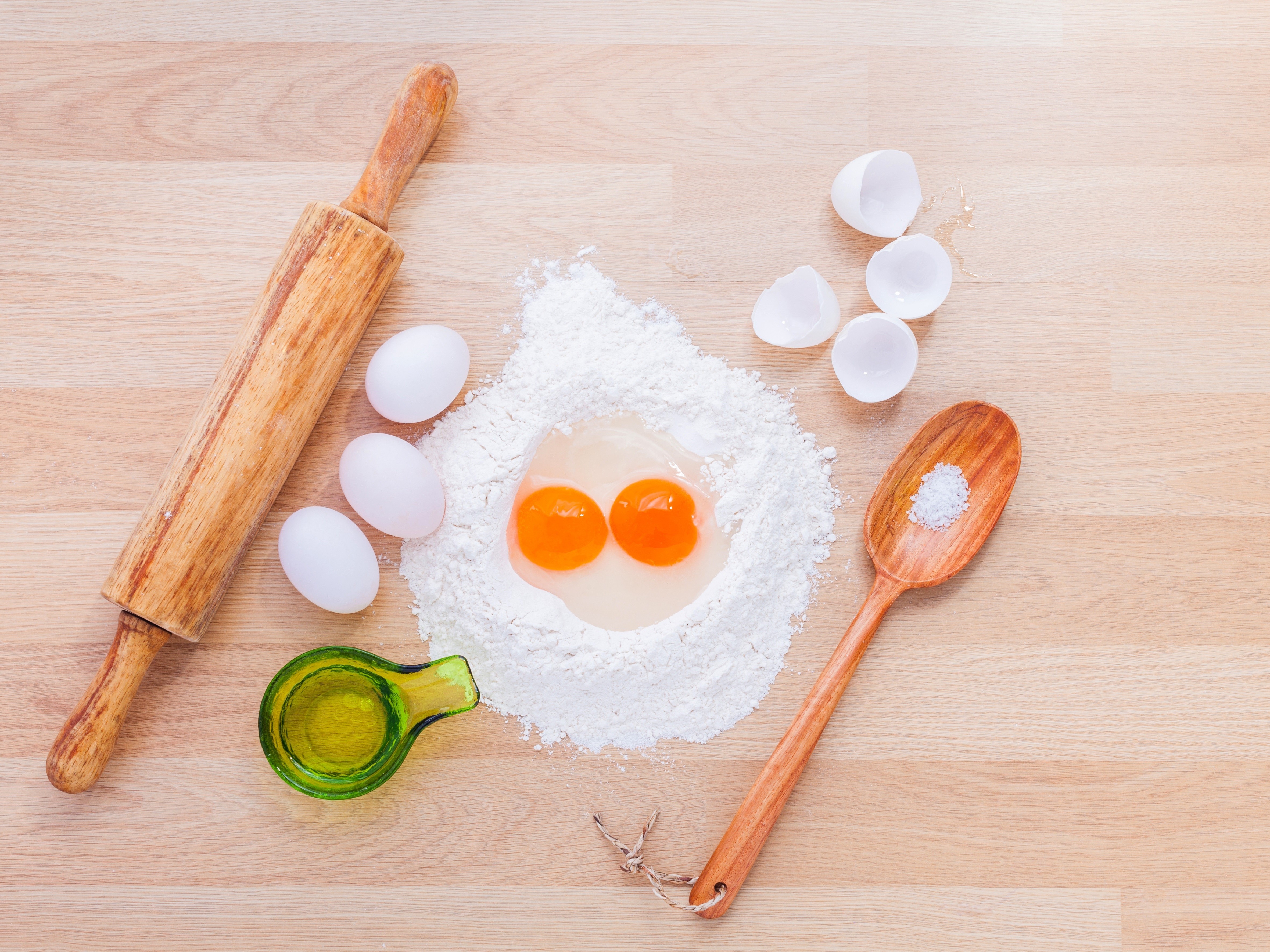 Flour, eggs, rolling pin, and spoon on a wooden table HD Wallpaper