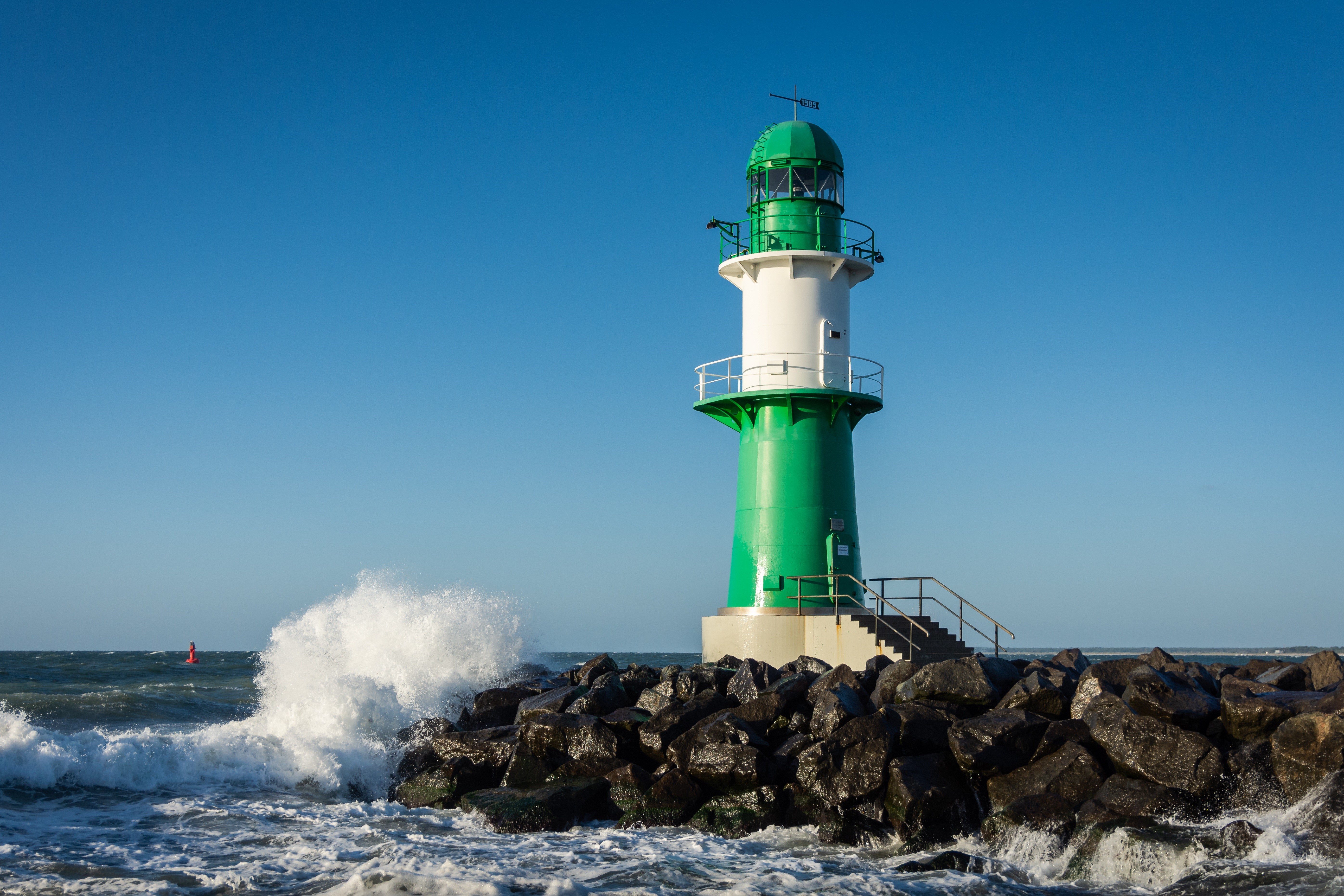 Lighthouse on a rocky shore with waves in Germany HD Wallpaper