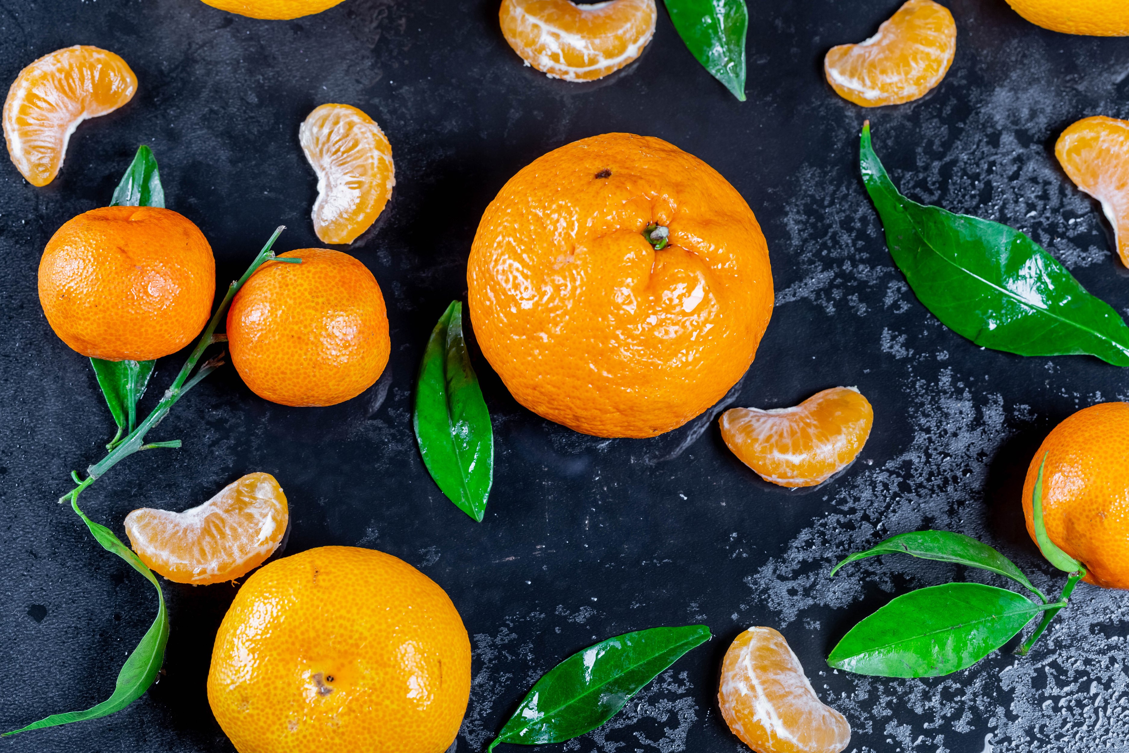 Tangerines and leaves on a dark surface HD Wallpaper