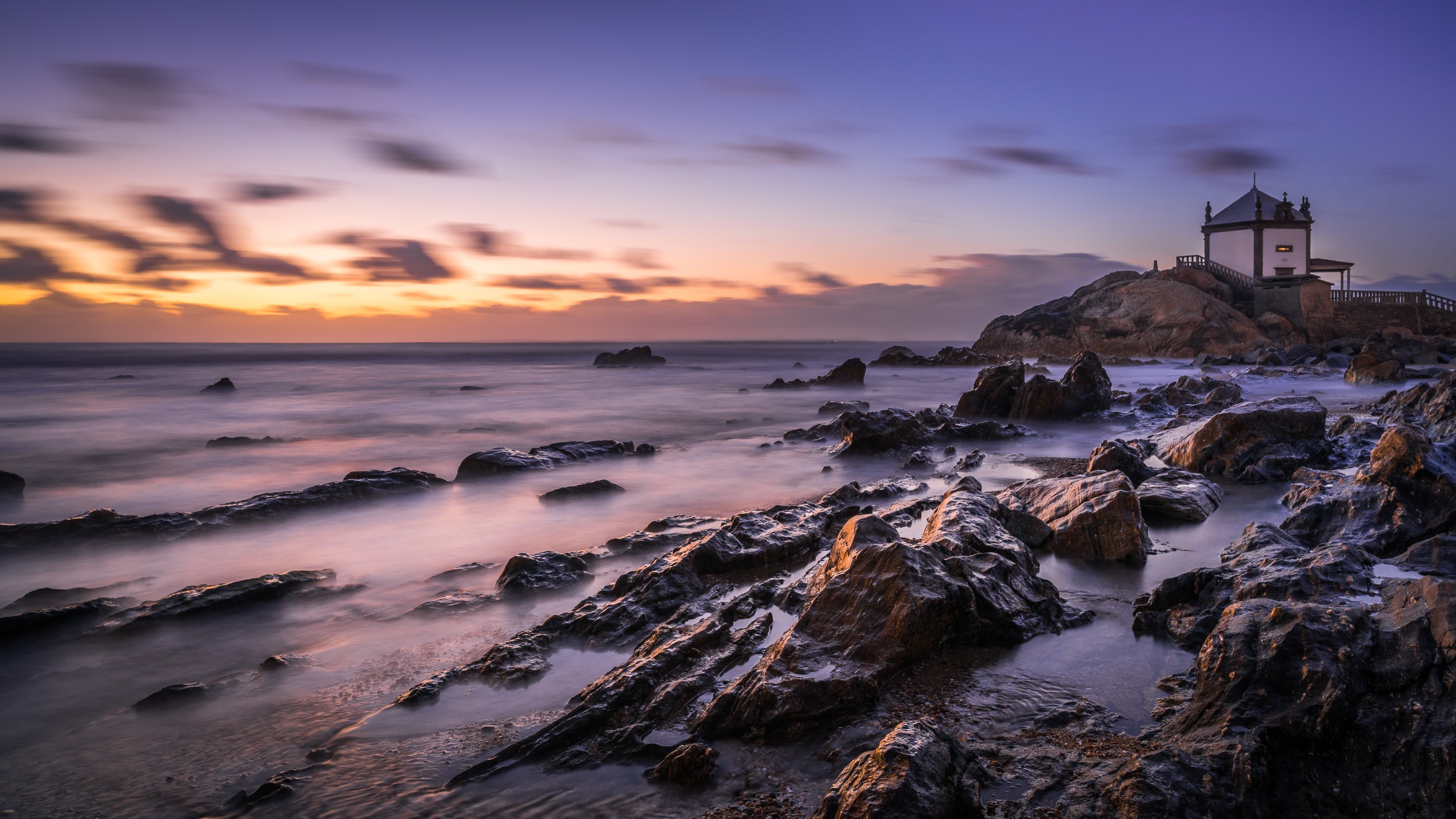 Capela do Senhor da Pedra chapel on rocky coast at sunset HD Wallpaper