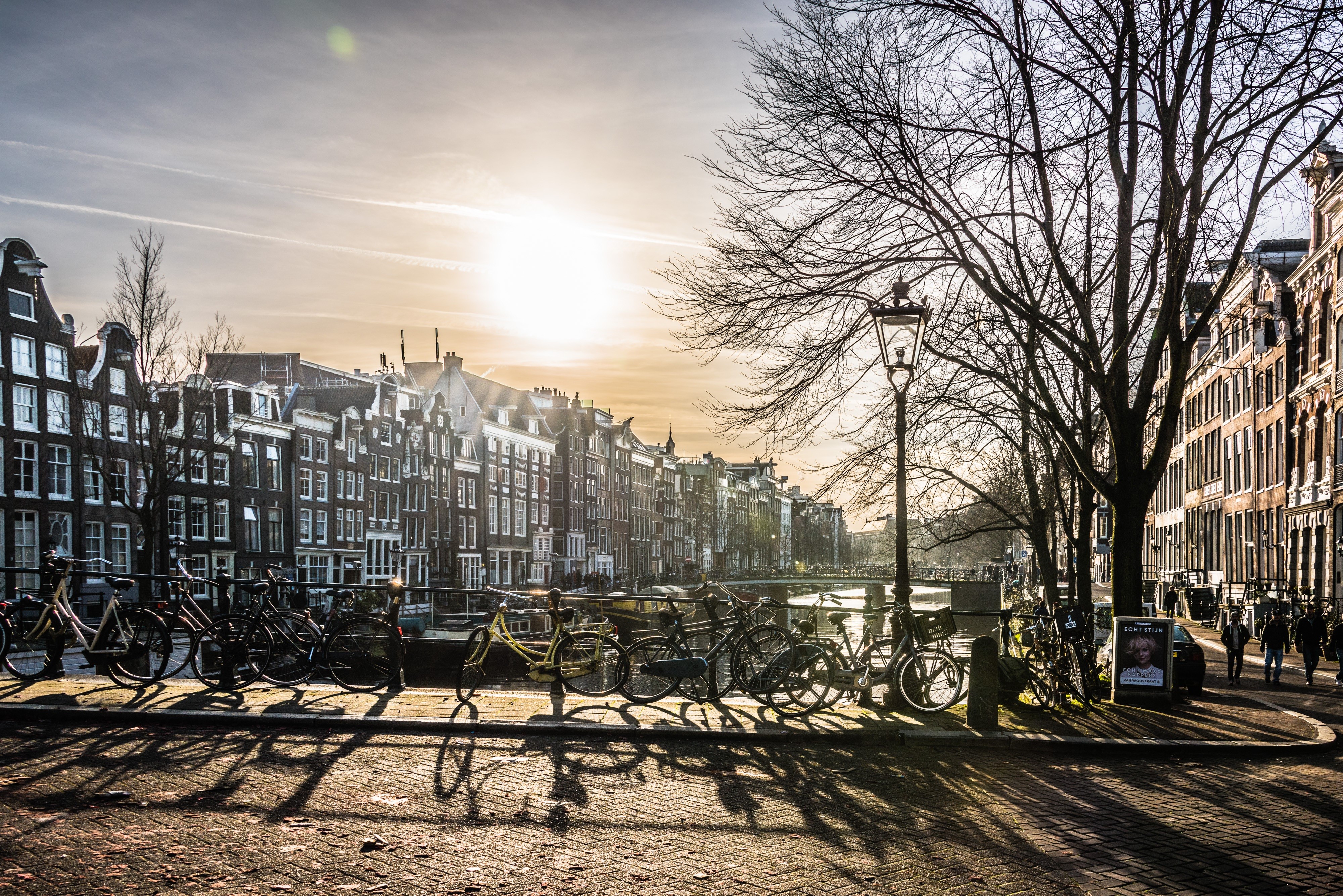 Amsterdam canal with bicycles and buildings at sunset HD Wallpaper