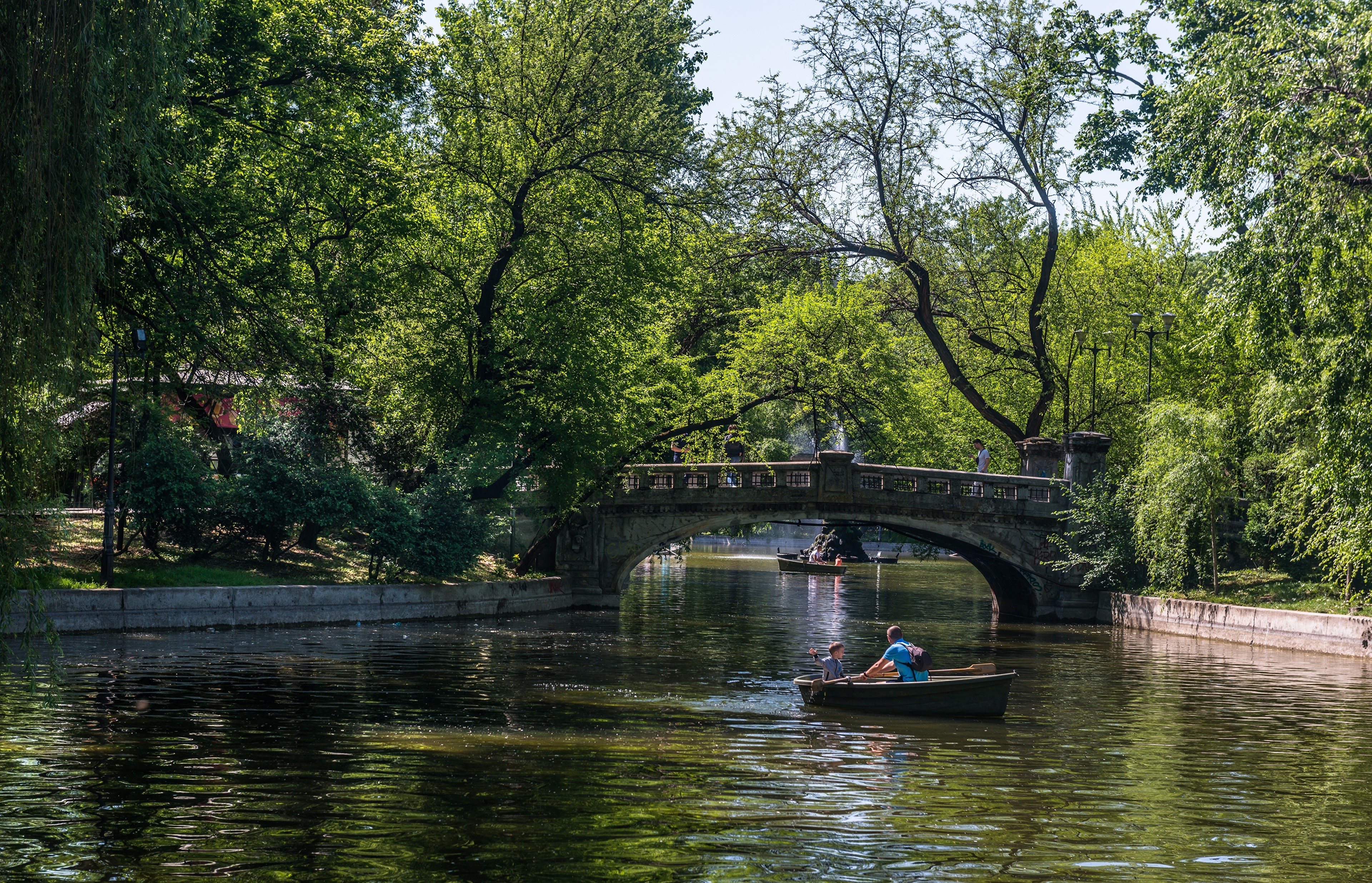 Boats on a canal under a bridge in a park HD Wallpaper