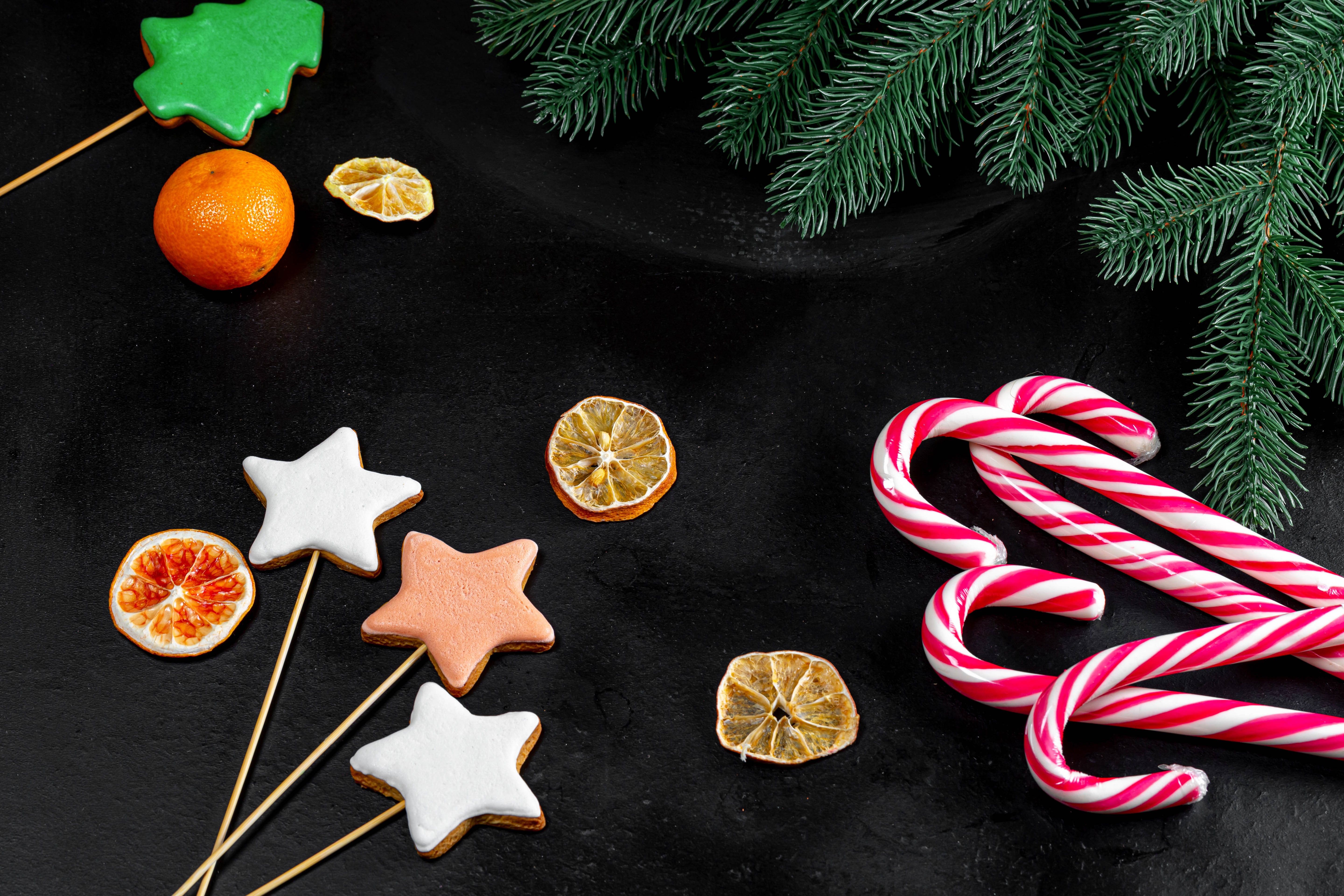 Christmas cookies, candy canes, and fir branches on black background HD Wallpaper