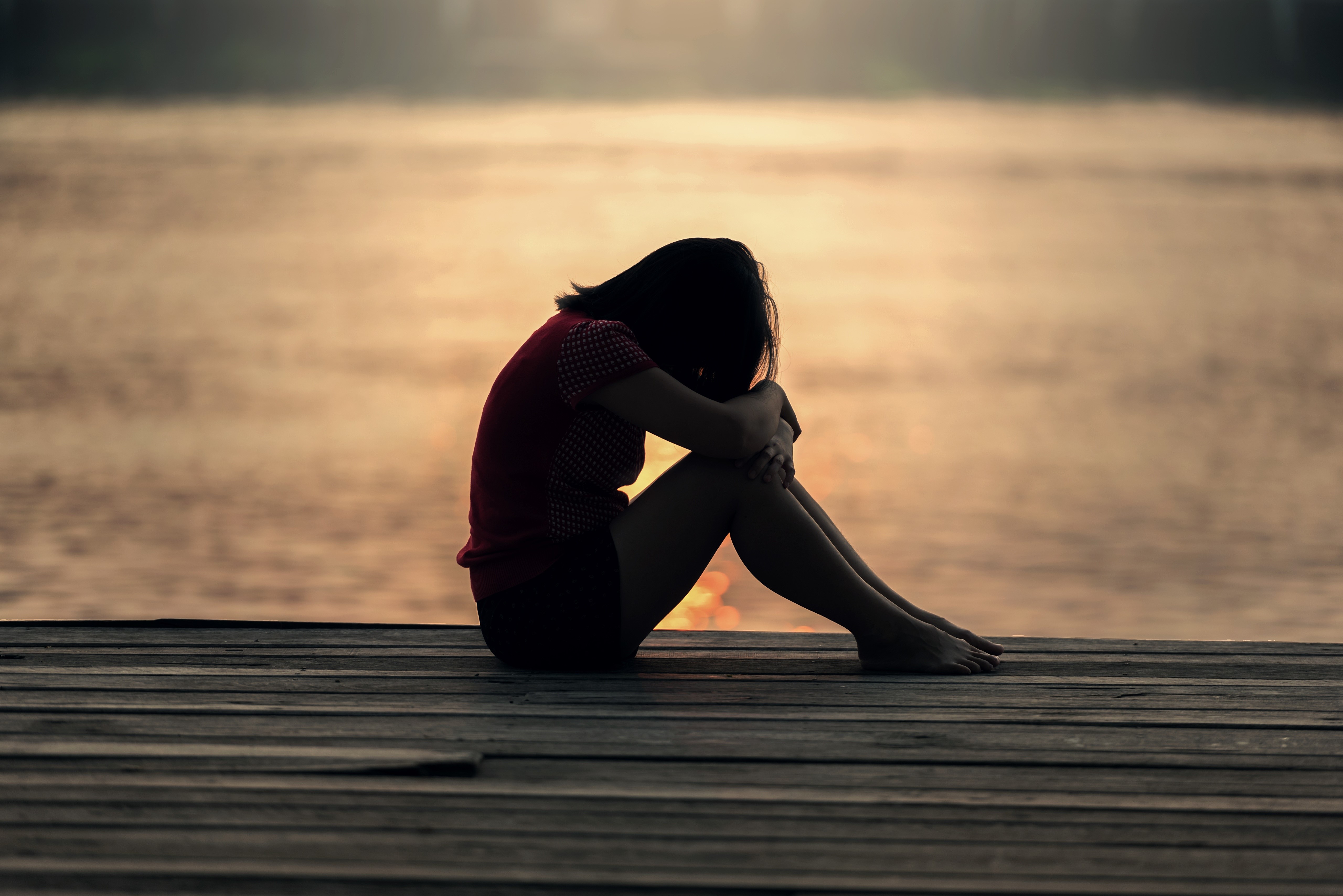 Silhouette of a person sitting on a dock HD Wallpaper