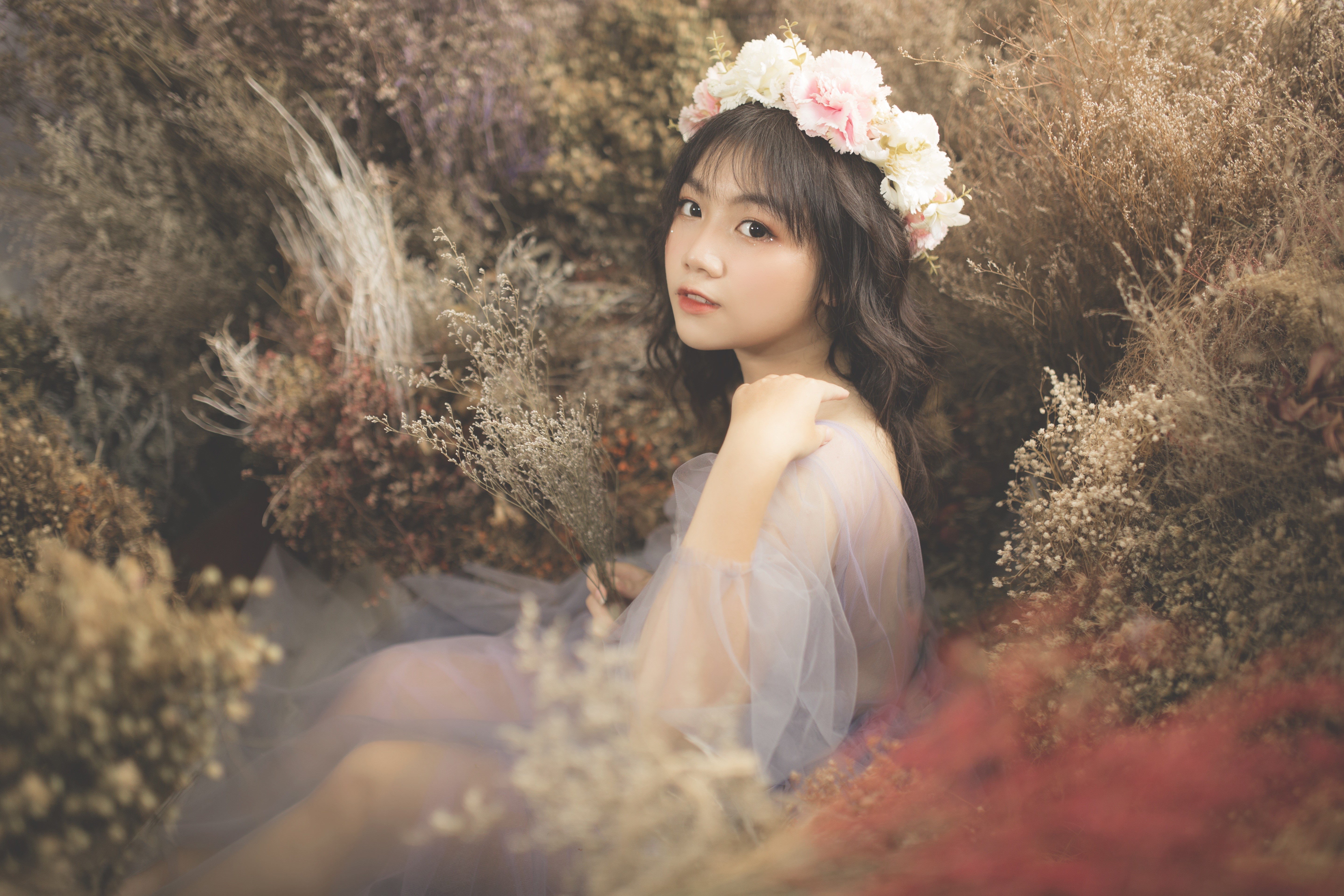 Brunette girl with flower wreath sitting in dried flowers HD Wallpaper