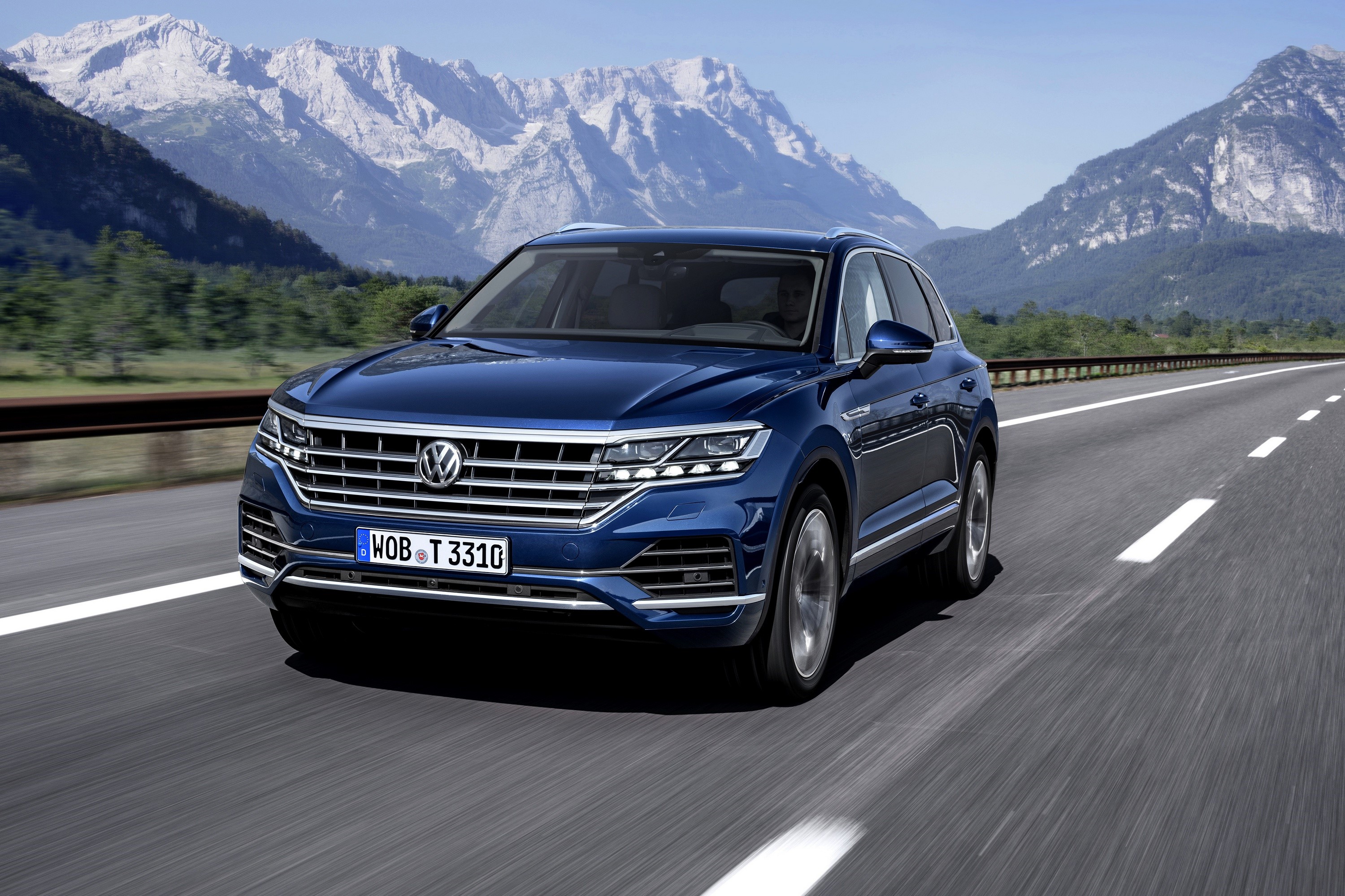 Blue Volkswagen Touareg driving on a highway with mountains HD Wallpaper