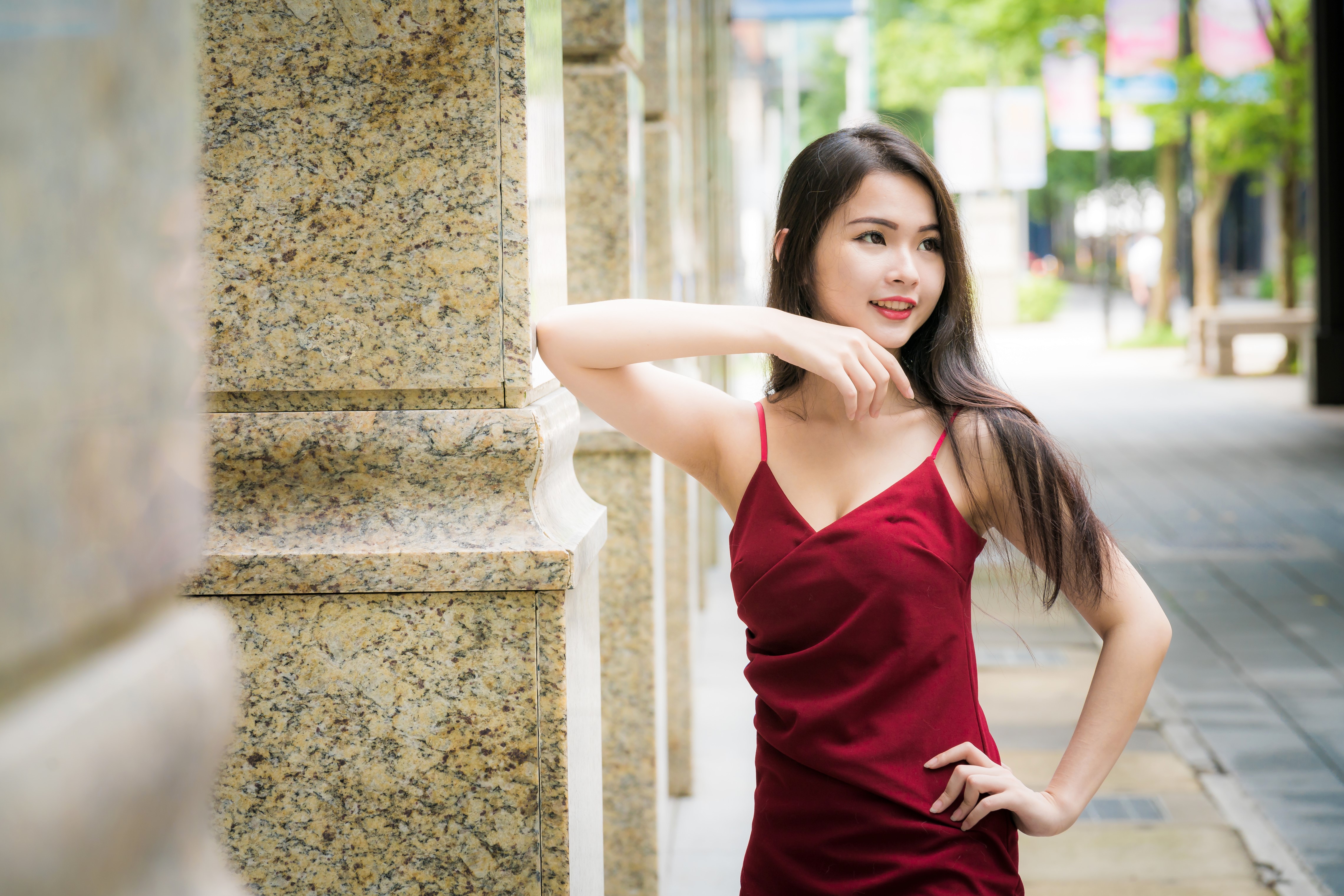 Asian woman in red dress posing by column HD Wallpaper