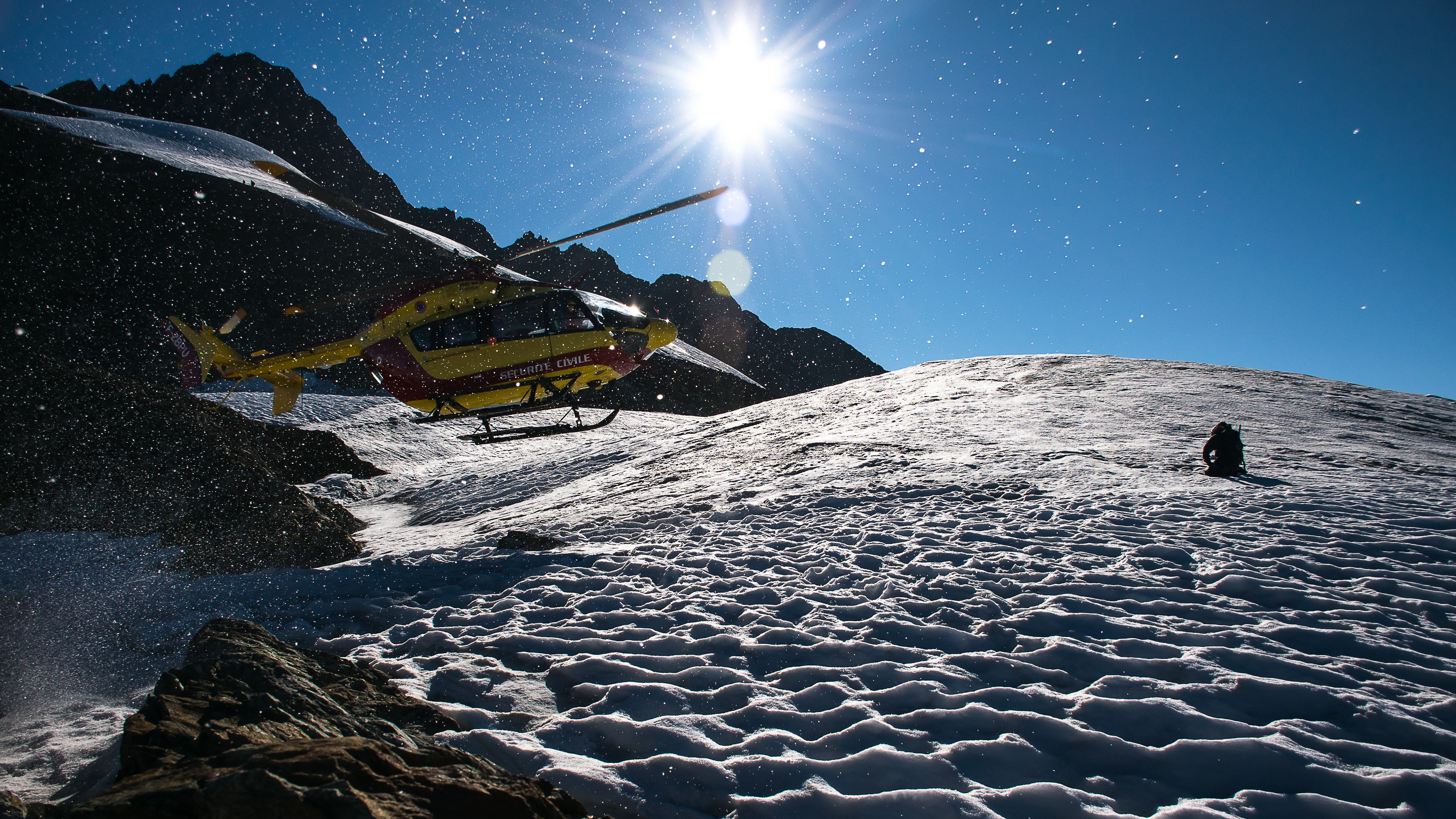Helicopter landing on a snowy mountain with sun HD Wallpaper