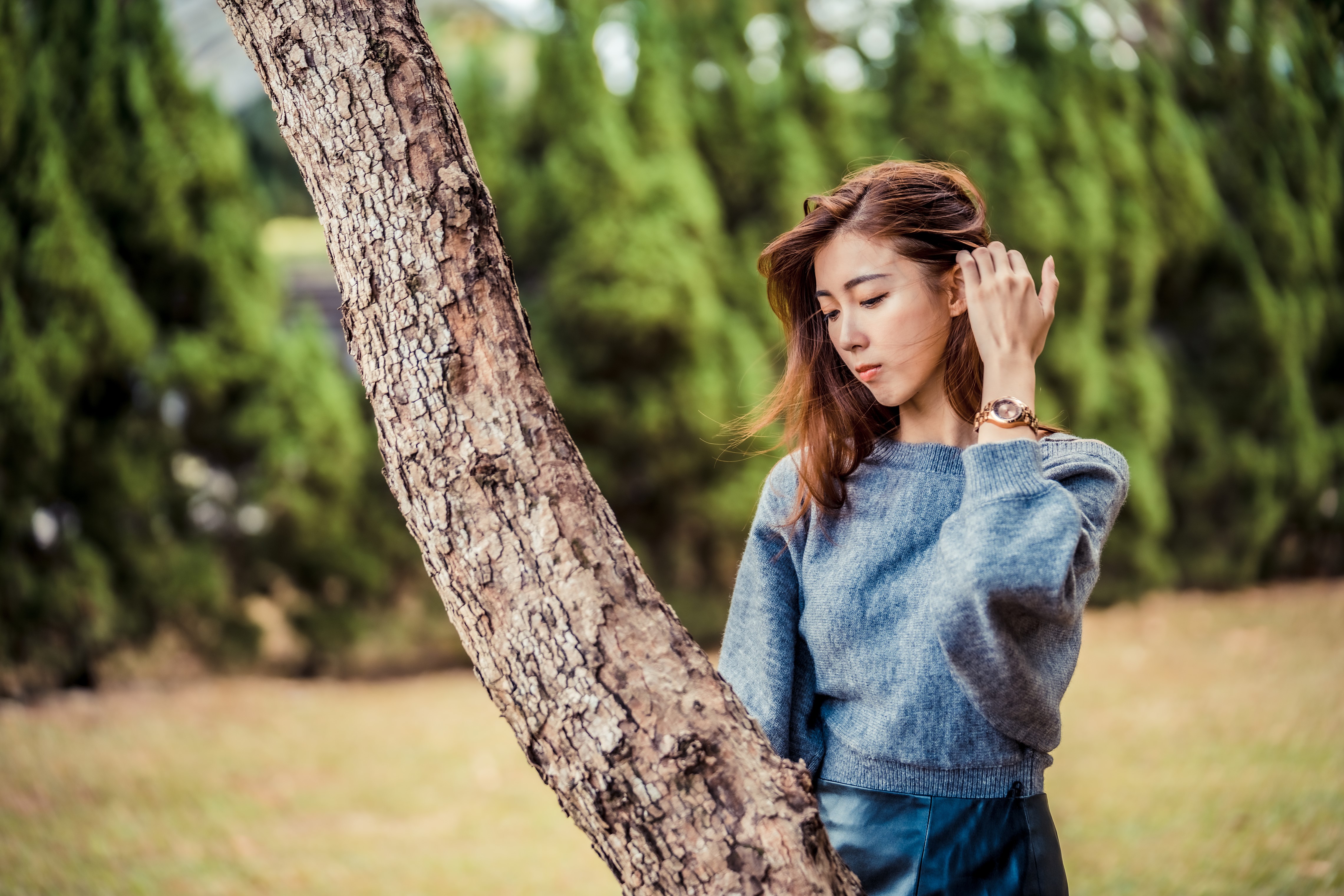 Asian woman in sweater by tree trunk HD Wallpaper