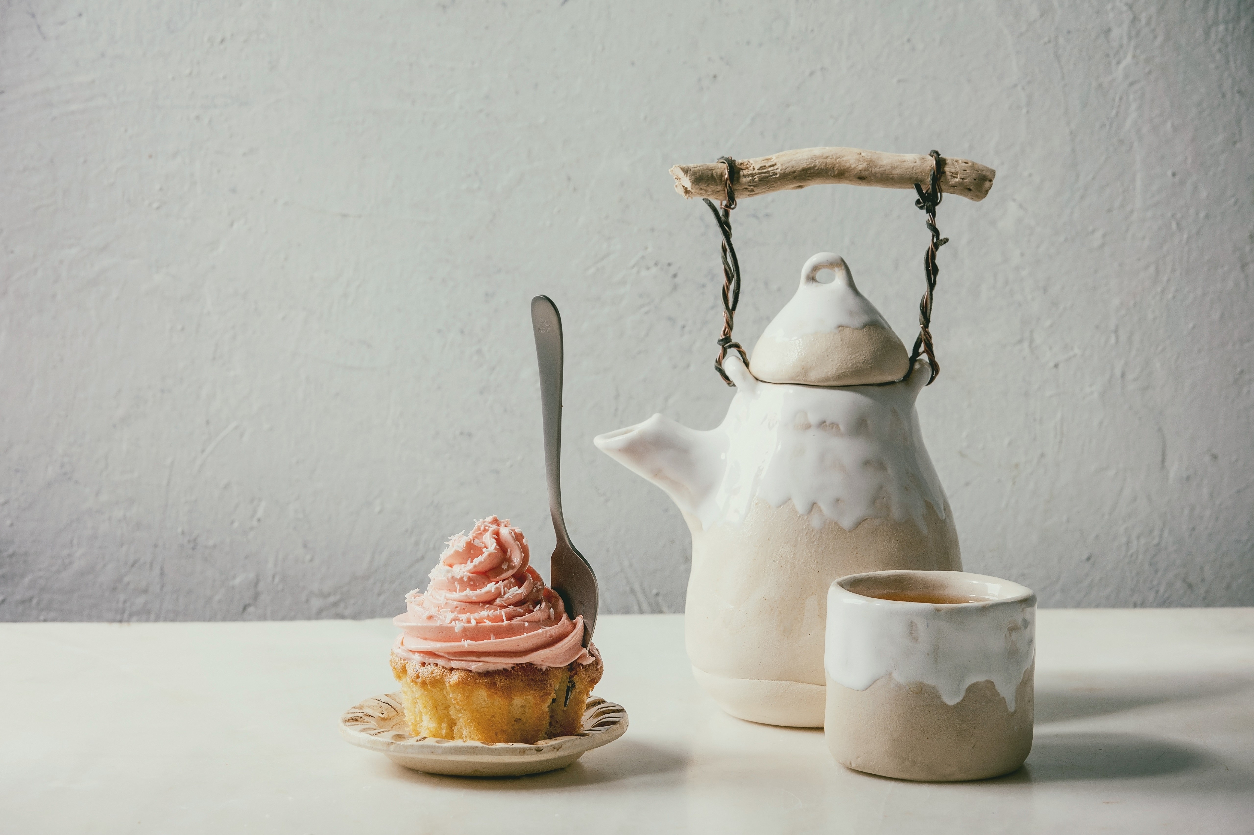 Cupcake with pink frosting next to a teapot and mug HD Wallpaper