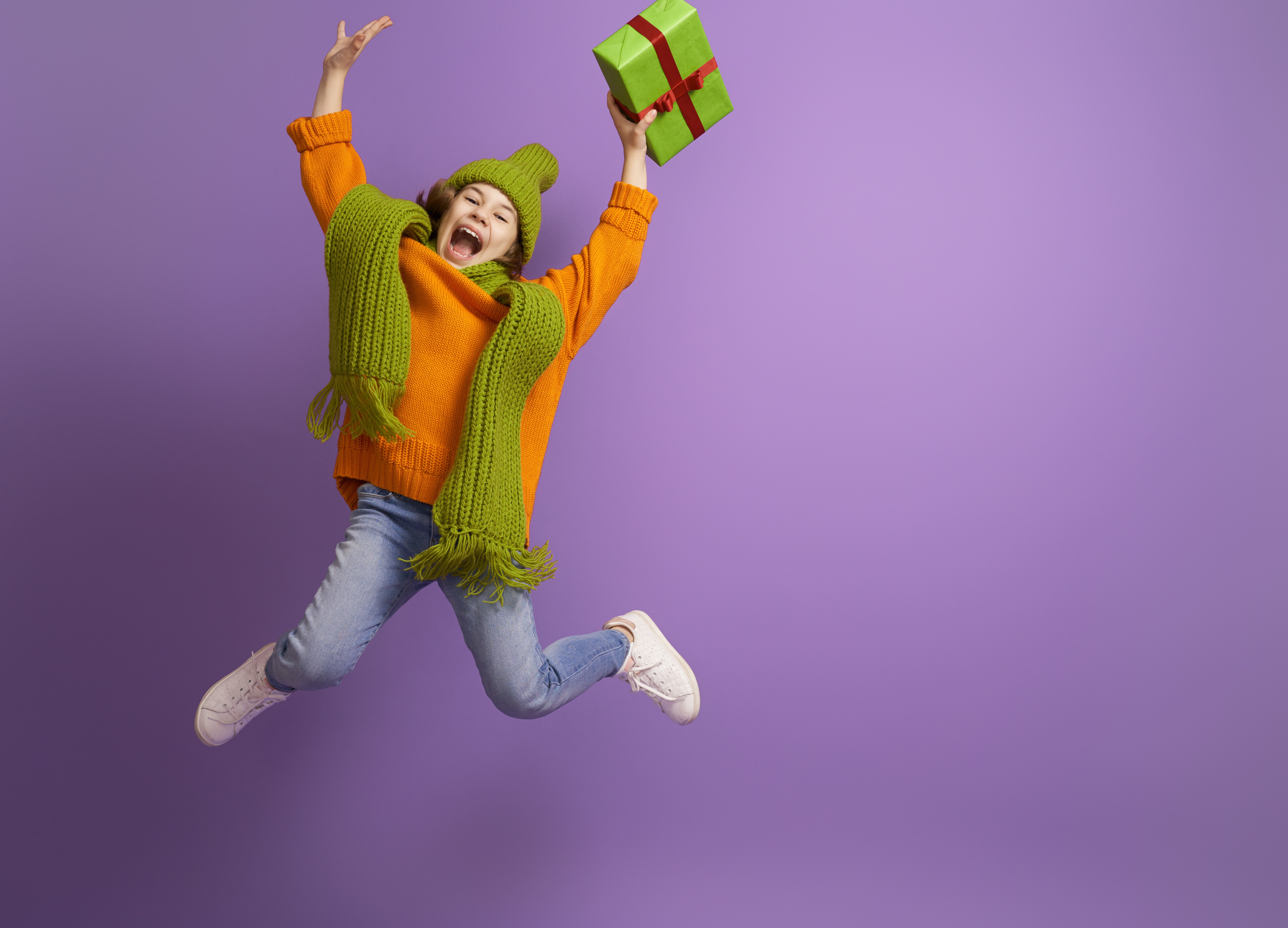 Girl in orange sweater jumping with gift HD Wallpaper