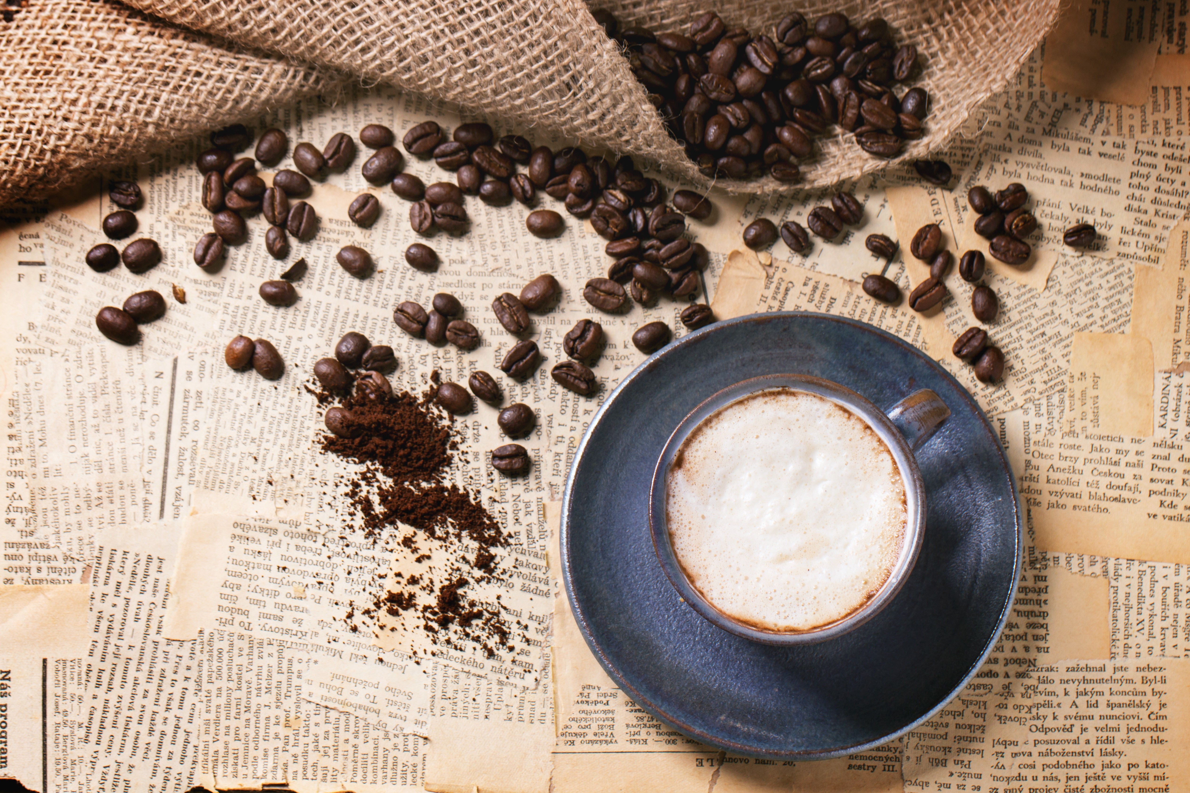 Coffee beans and cappuccino on old newspapers HD Wallpaper