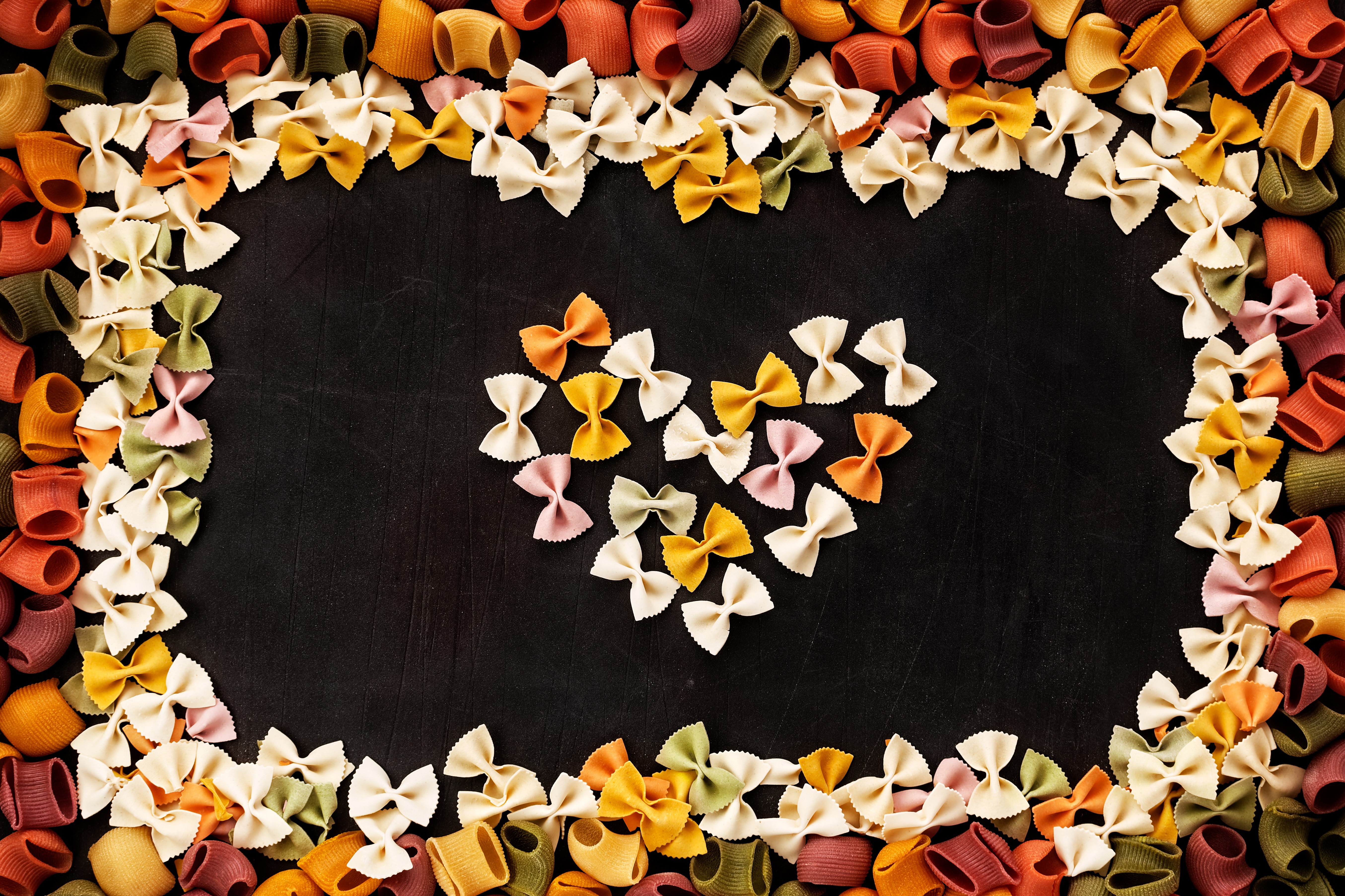 Heart shape made of colorful pasta on black background HD Wallpaper