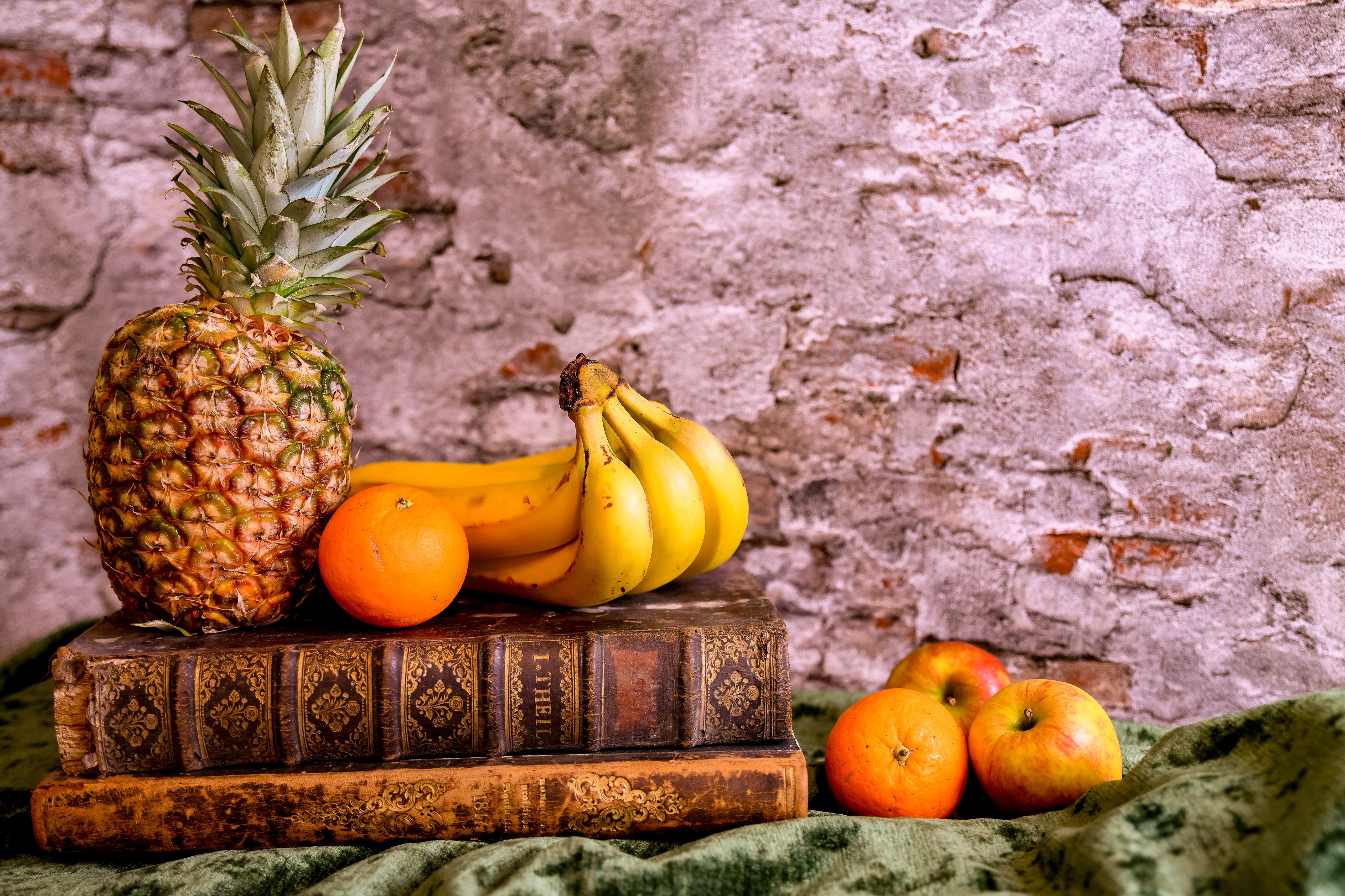 Still-life with pineapple, bananas, oranges, apples, and books HD Wallpaper