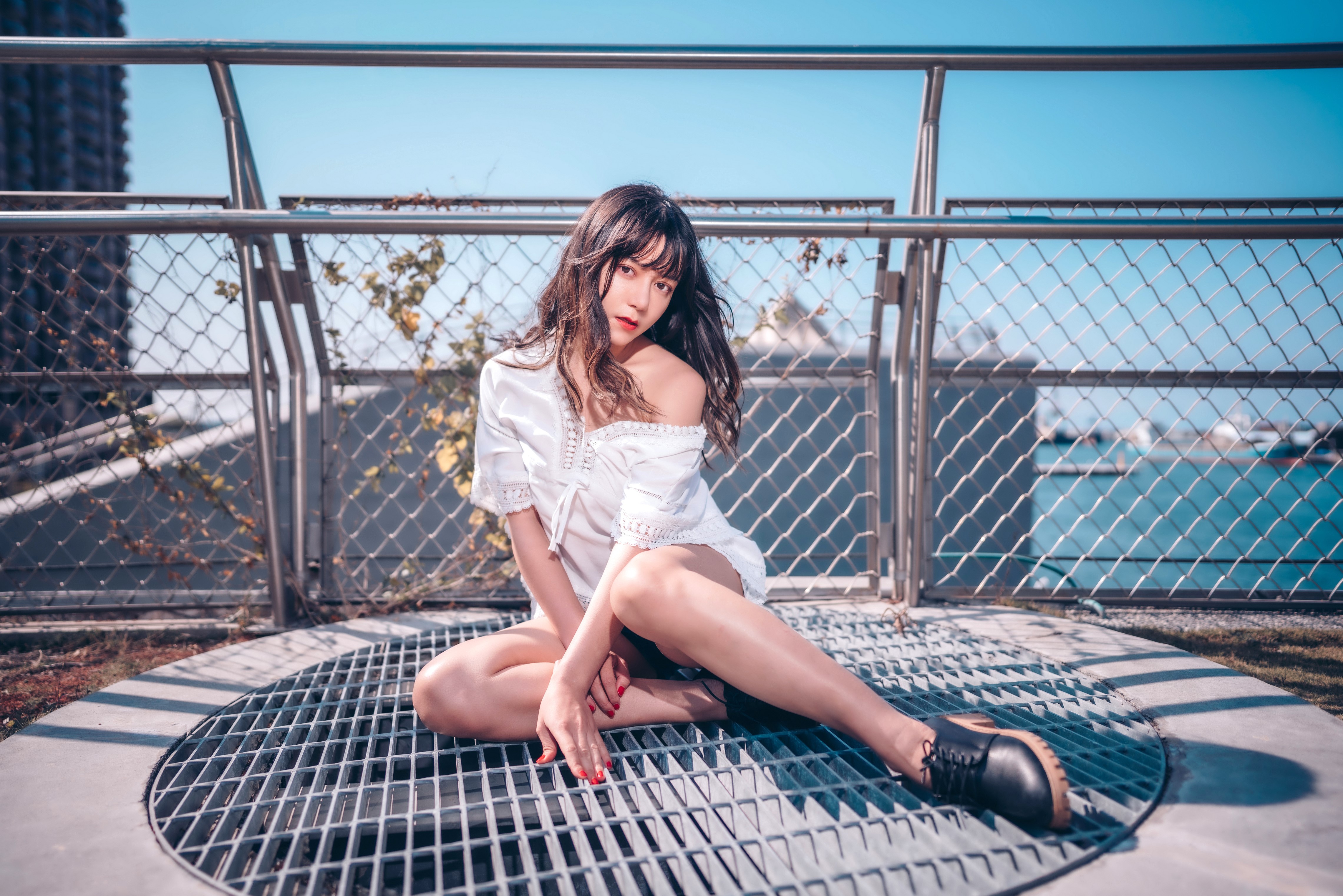 Asian woman sitting on a metal grate by the water HD Wallpaper