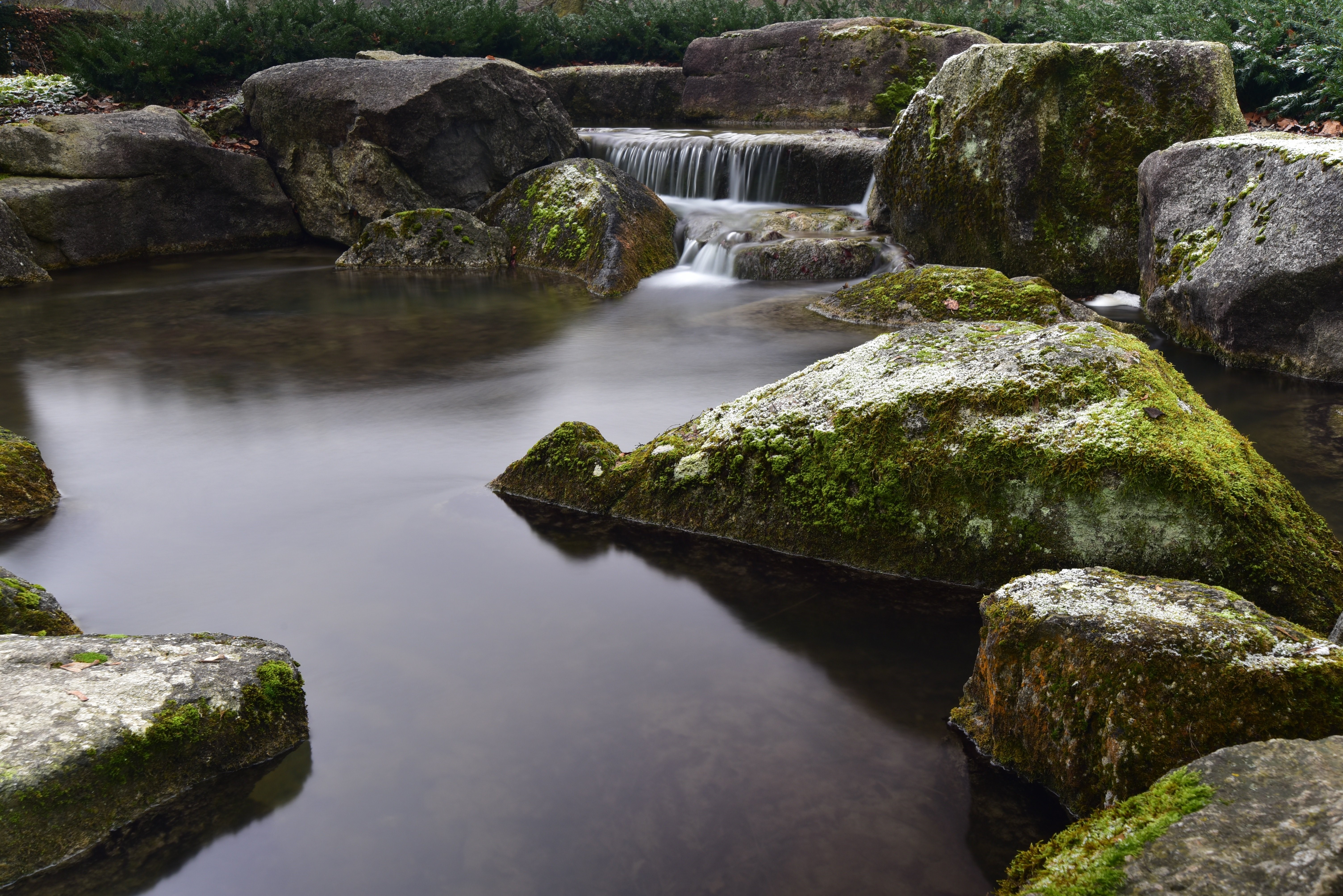 Mossy stones in a stream with a small waterfall HD Wallpaper