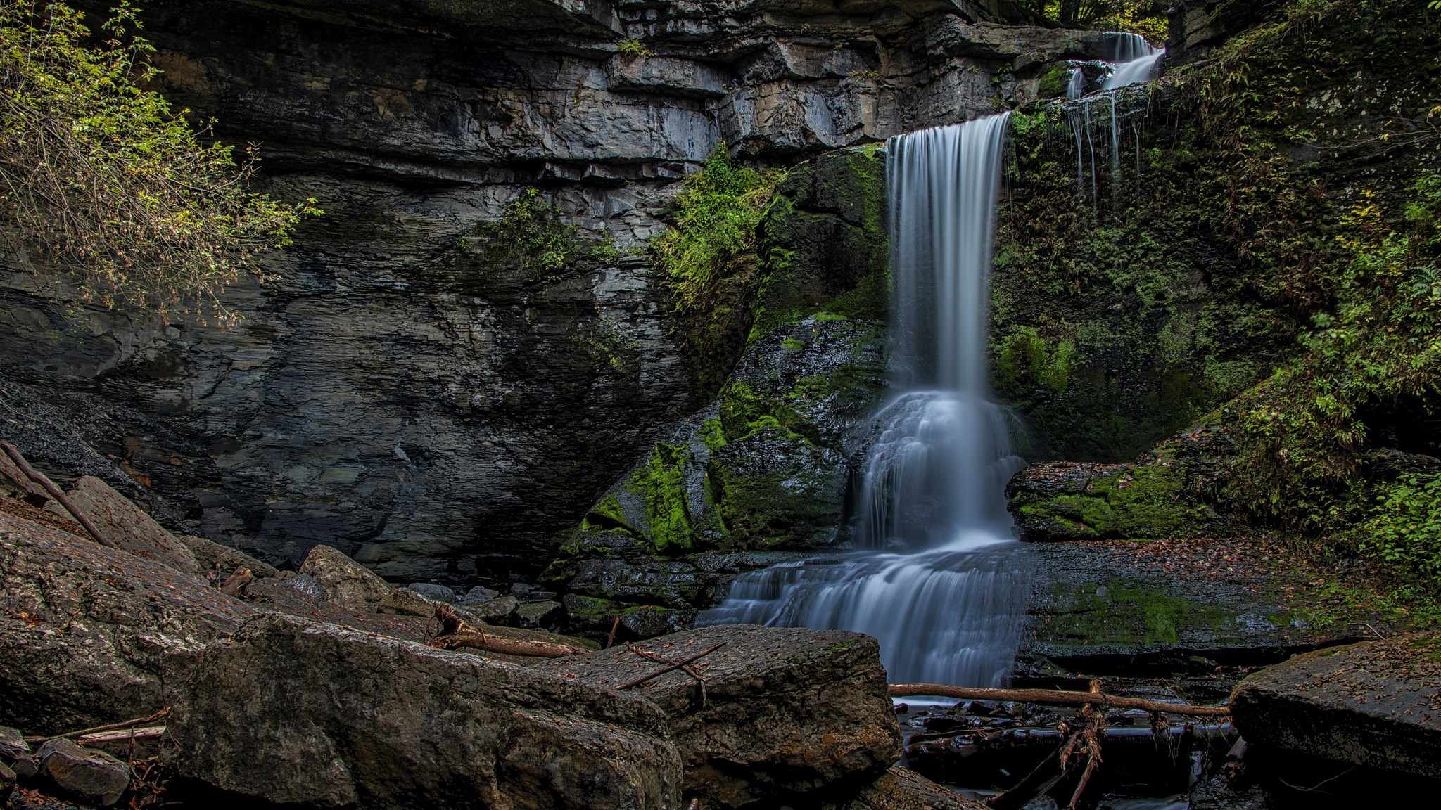 Waterfall cascading over mossy rocks in a forest HD Wallpaper
