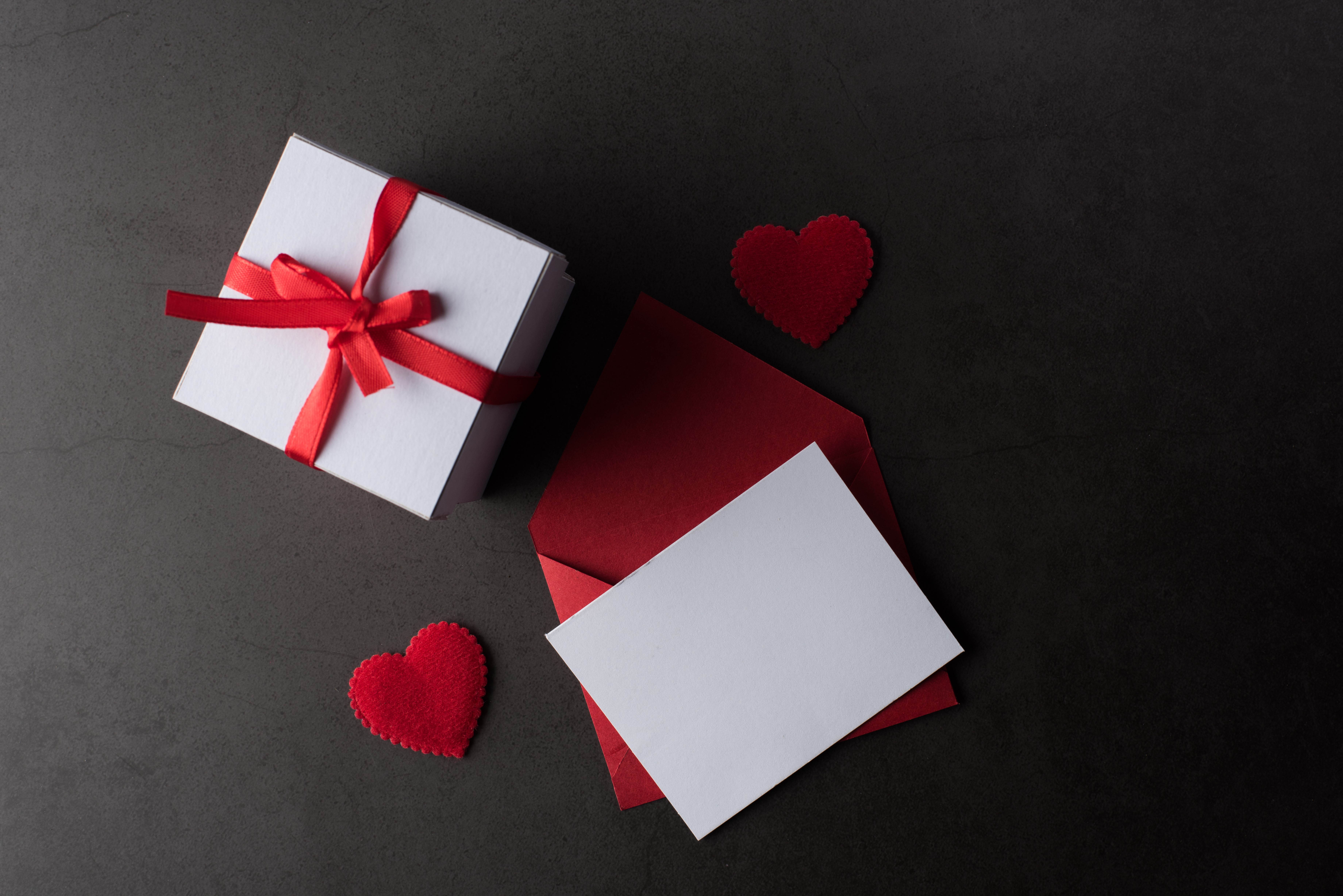 White gift box with red ribbon, red envelope, and white card on gray background HD Wallpaper