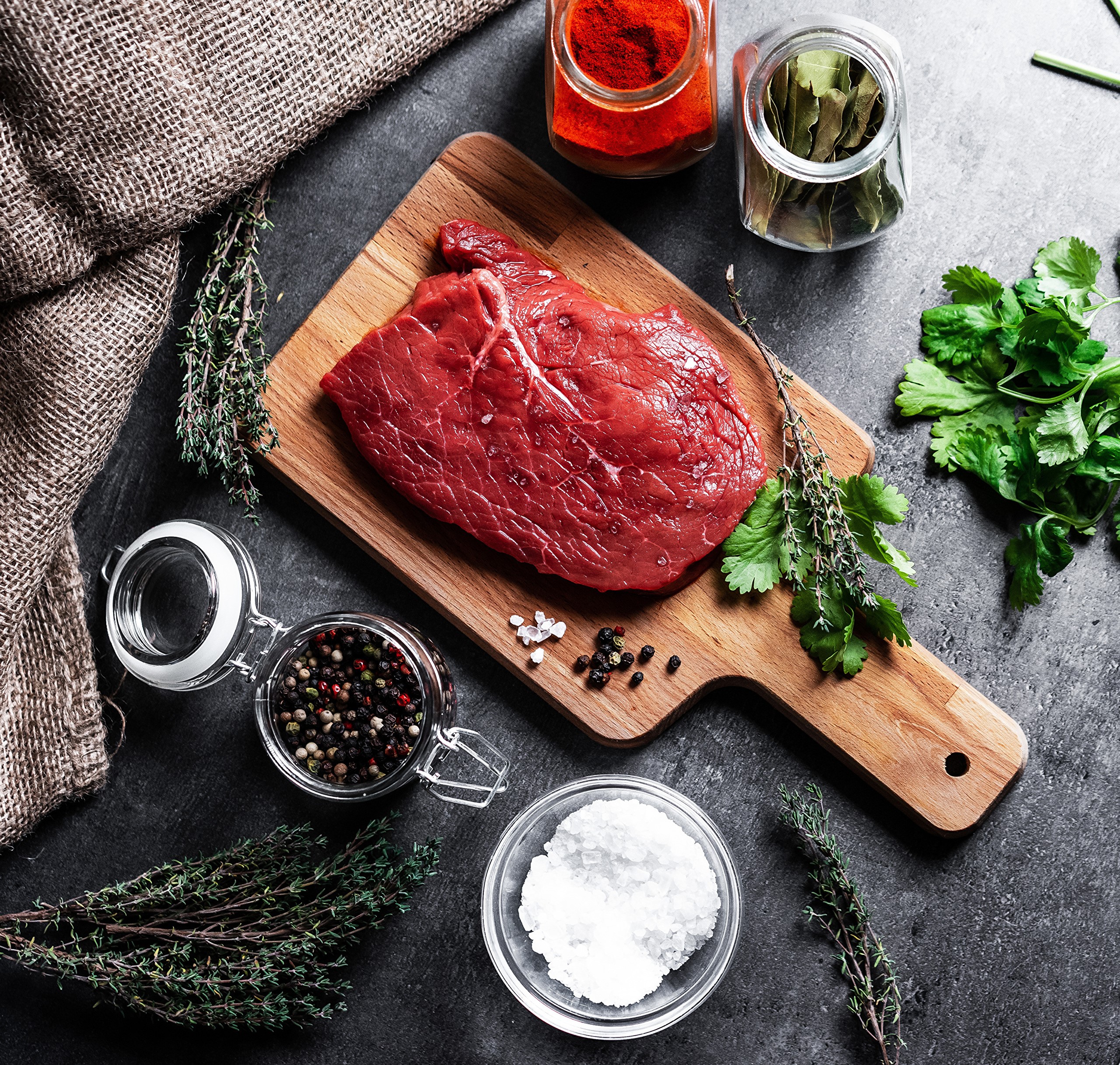 Raw steak with spices and herbs on a cutting board HD Wallpaper