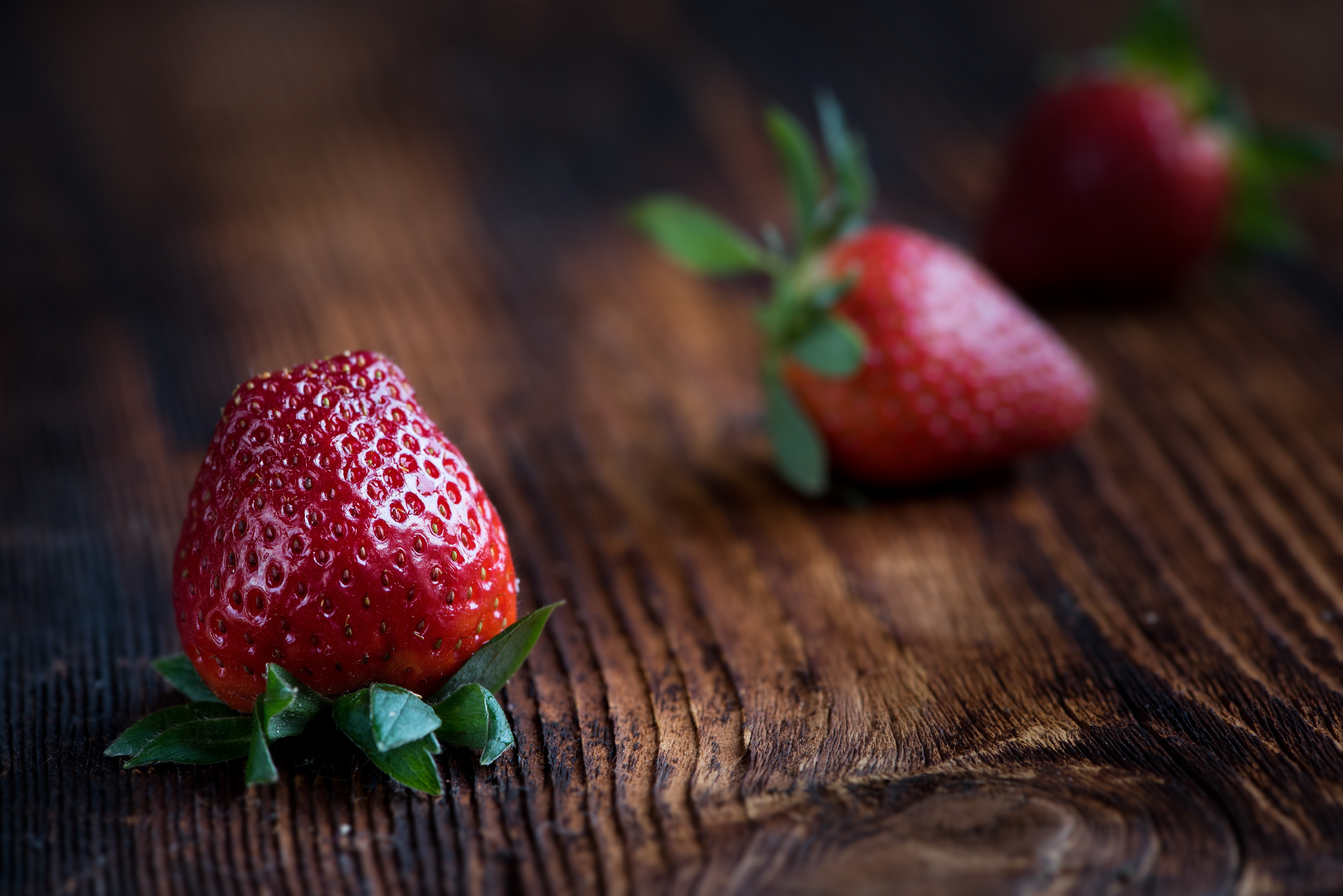 Close-up of a strawberry on a wooden surface HD Wallpaper