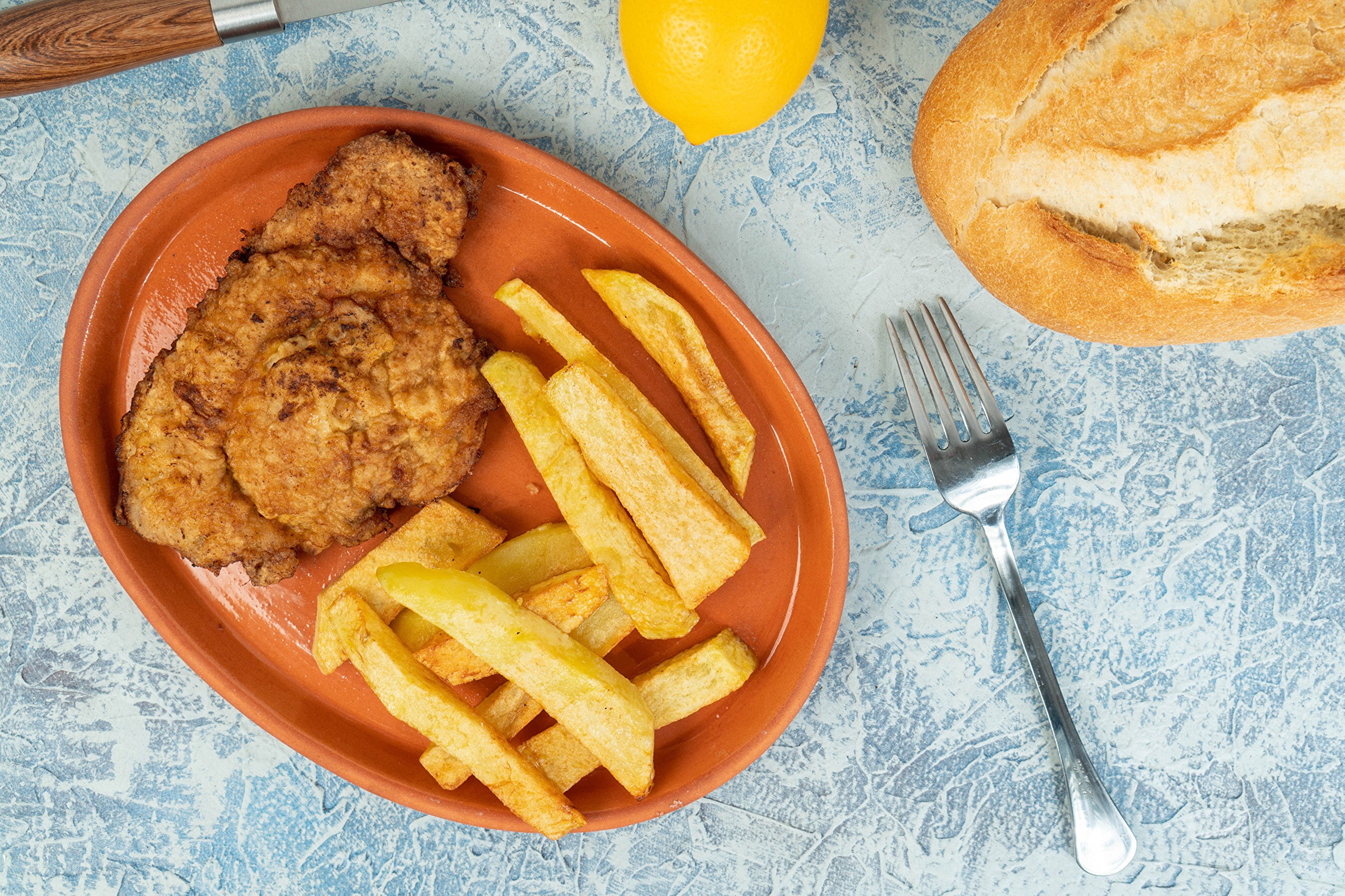 Fried meat and french fries on a plate with lemon and bread HD Wallpaper