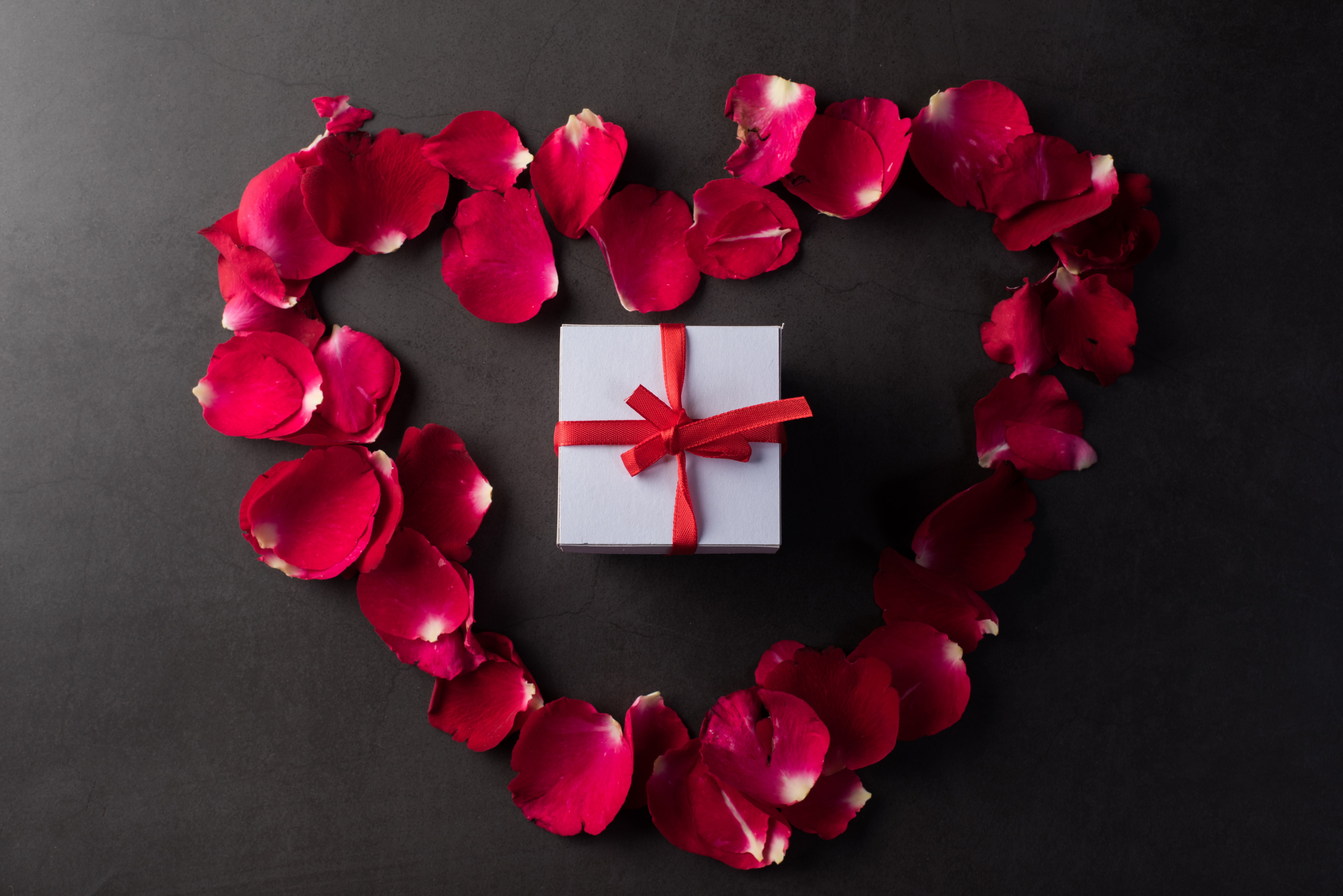 Gift box surrounded by rose petals in a heart shape HD Wallpaper