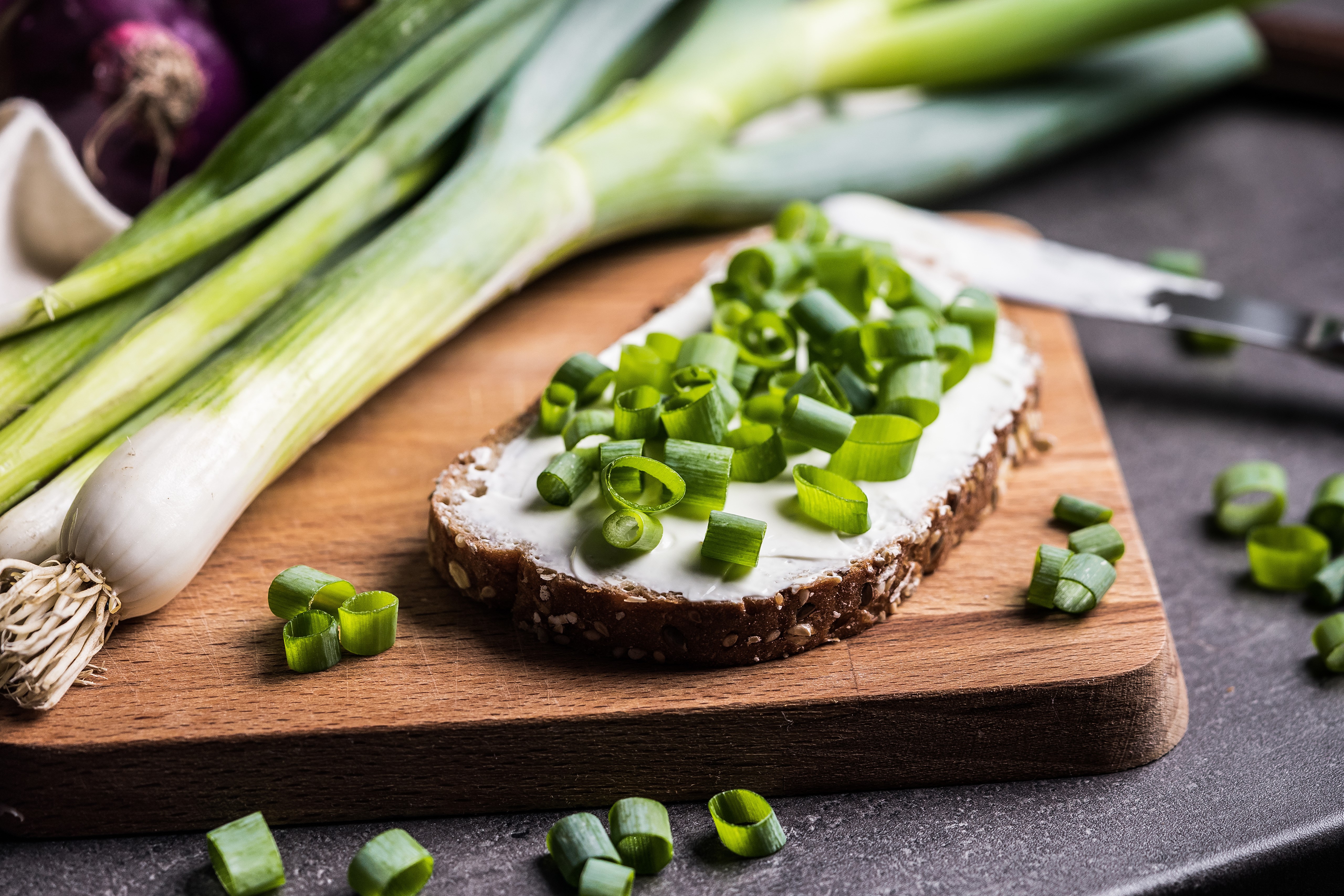 Scallions and bread with cream cheese on cutting board HD Wallpaper