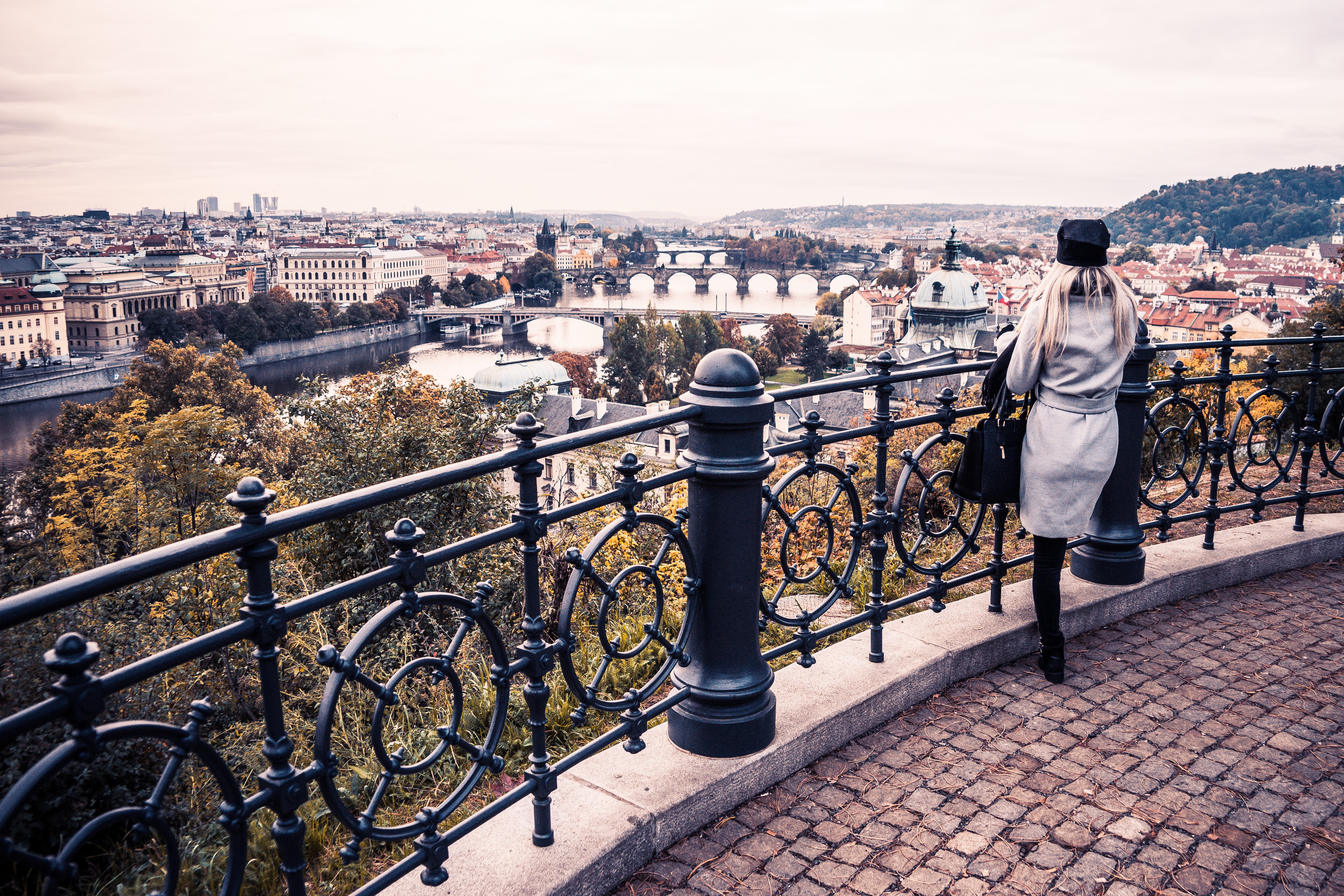 Woman overlooking Prague cityscape with bridges and river HD Wallpaper