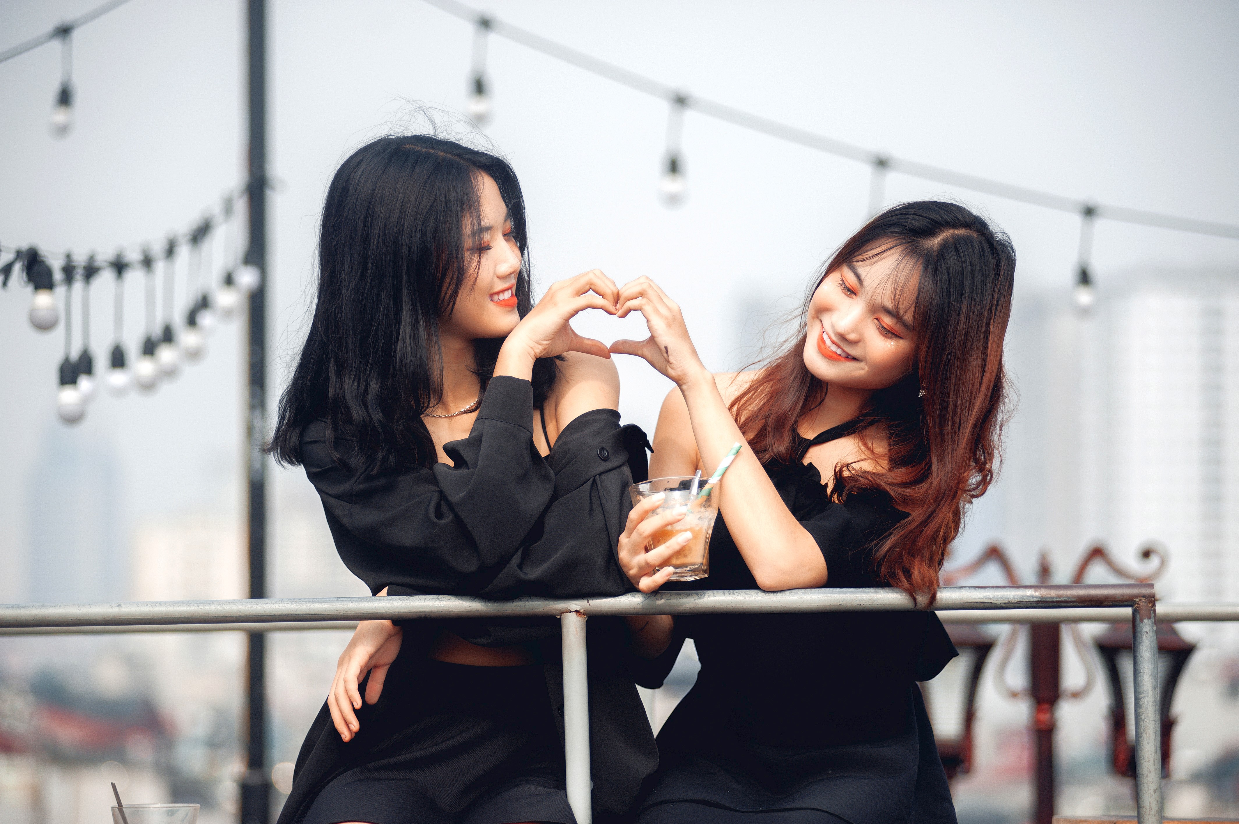 Two Asian women making a heart shape with their hands HD Wallpaper