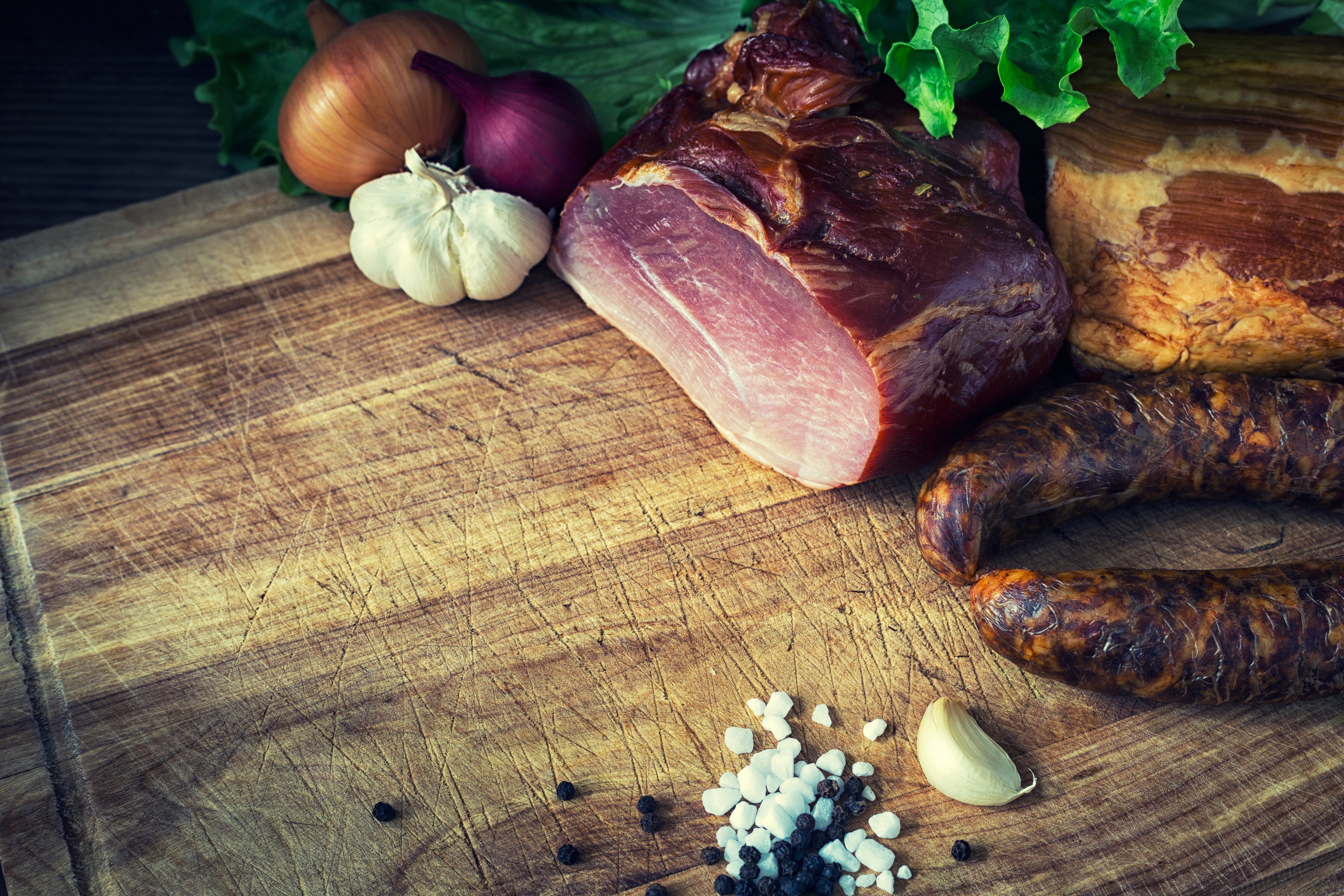 Meat products, ham, sausage, garlic, and onion on a cutting board HD Wallpaper