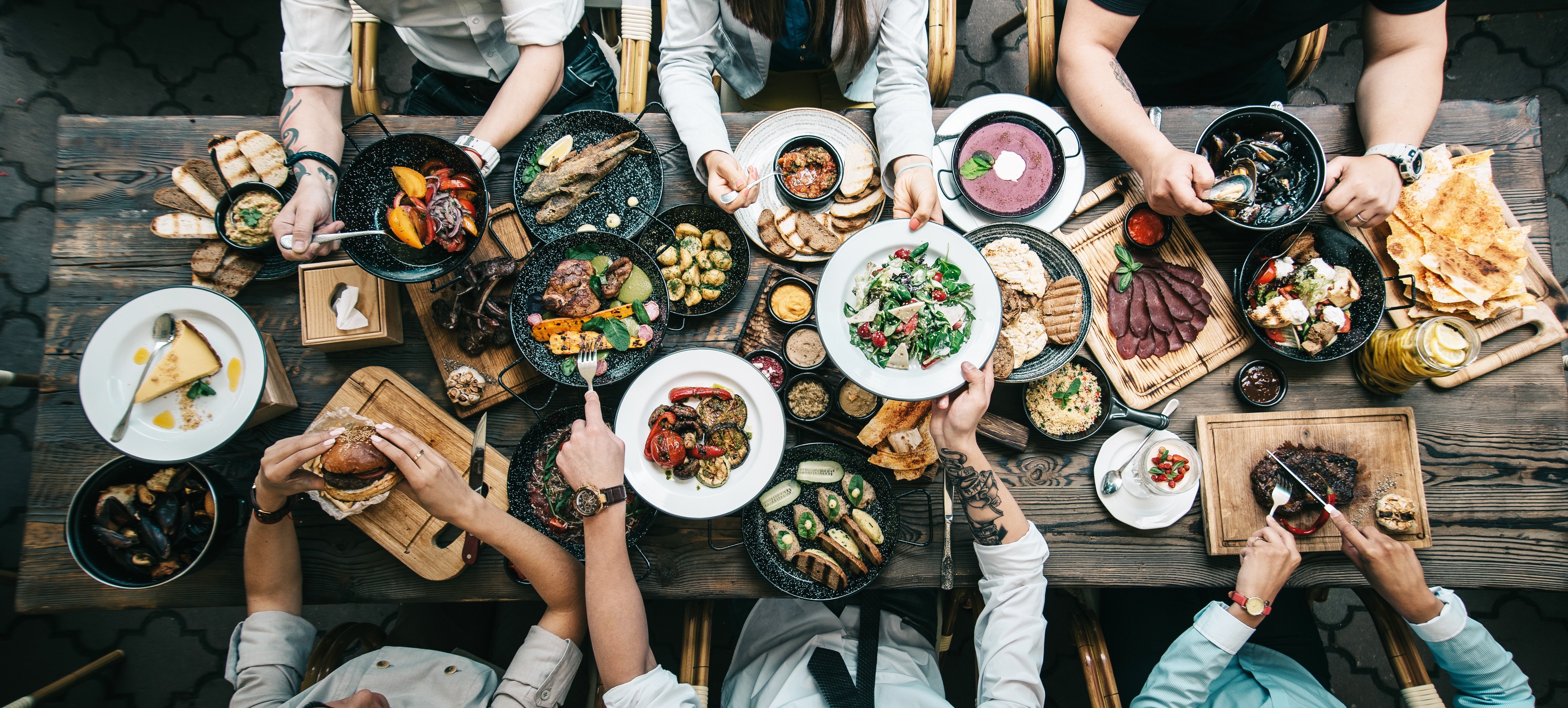 Many people eating at a table with many dishes HD Wallpaper