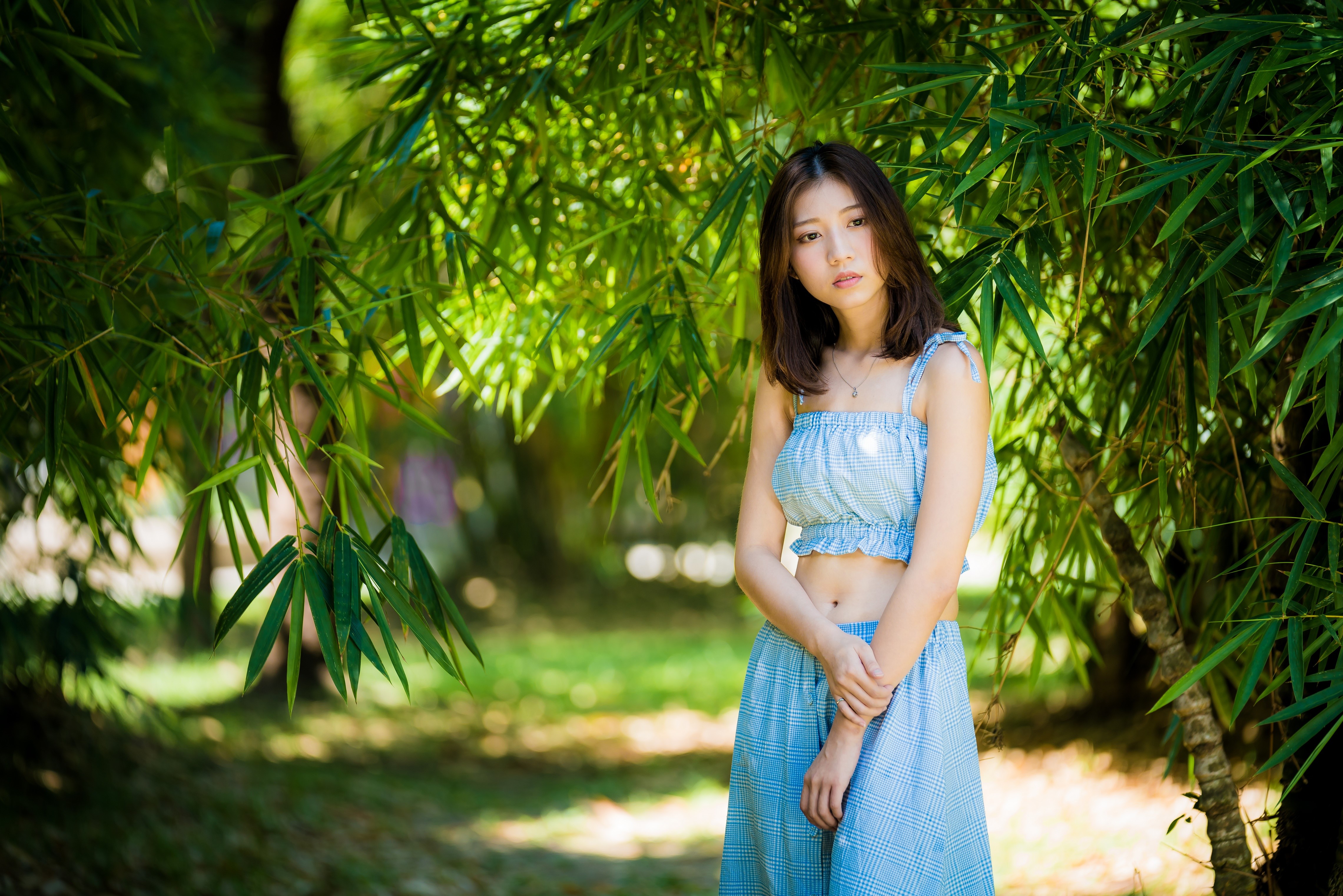 Asian woman with brown hair posing under bamboo branches HD Wallpaper