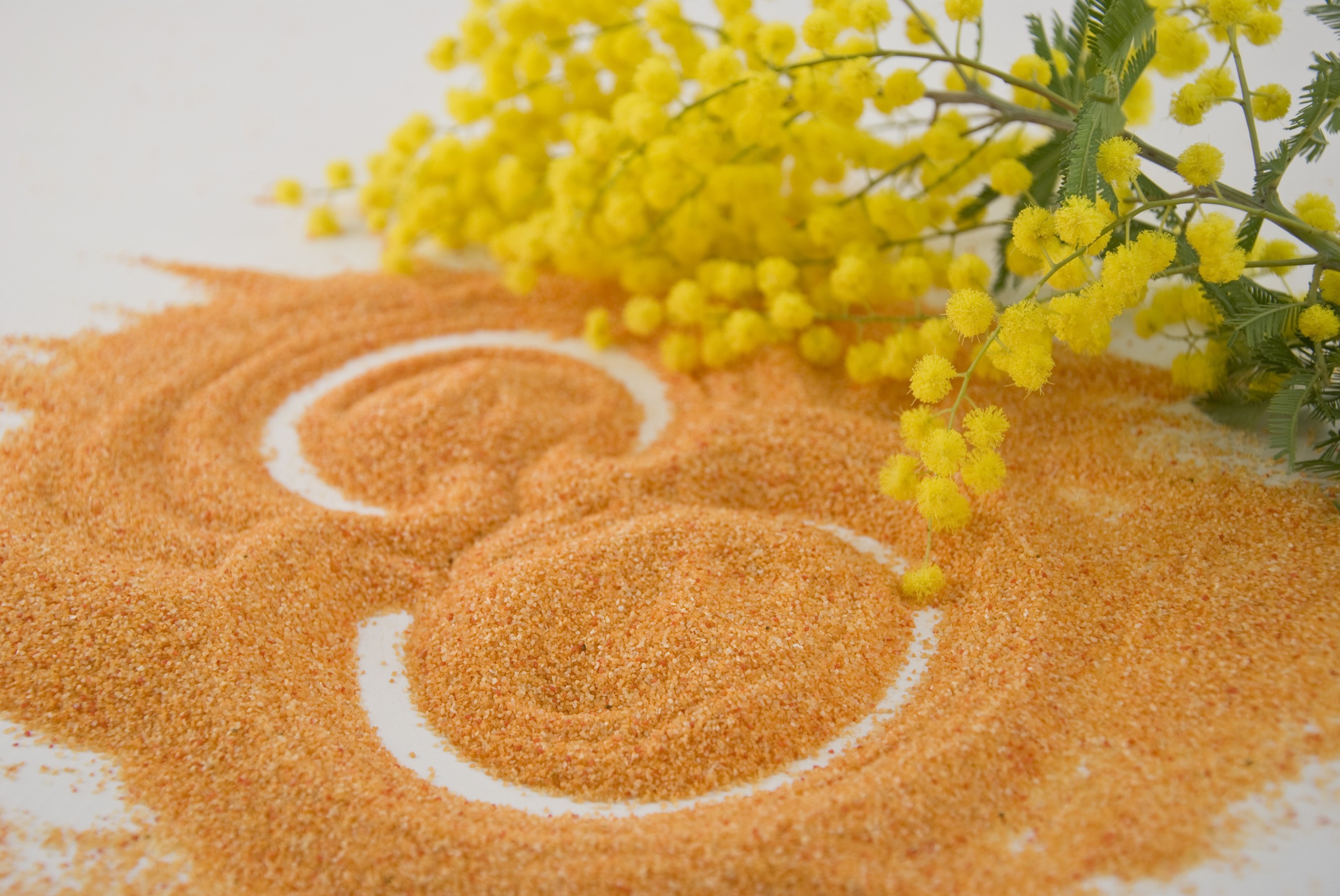 Orange sand forming the number 8 with mimosa flowers HD Wallpaper