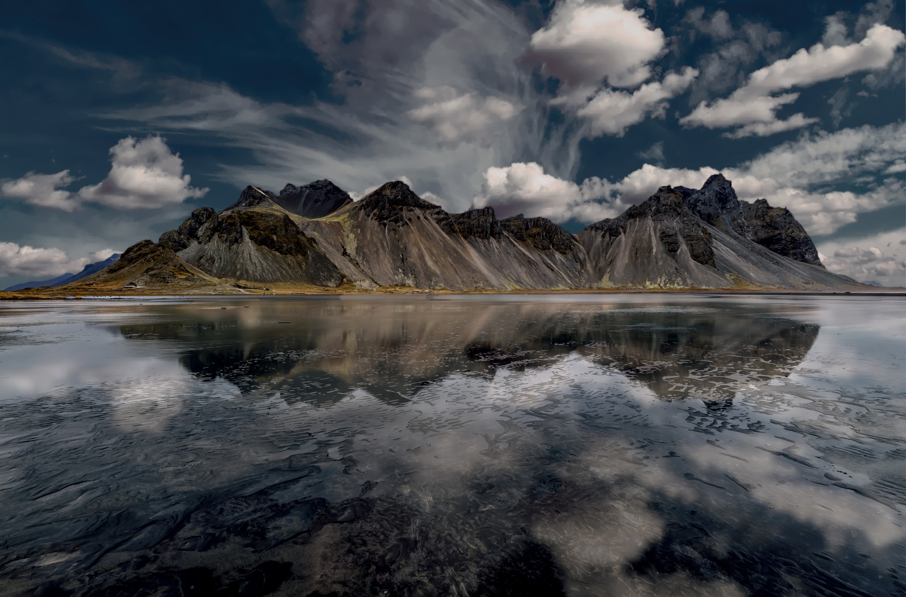 Mountains reflected in water under a cloudy sky HD Wallpaper