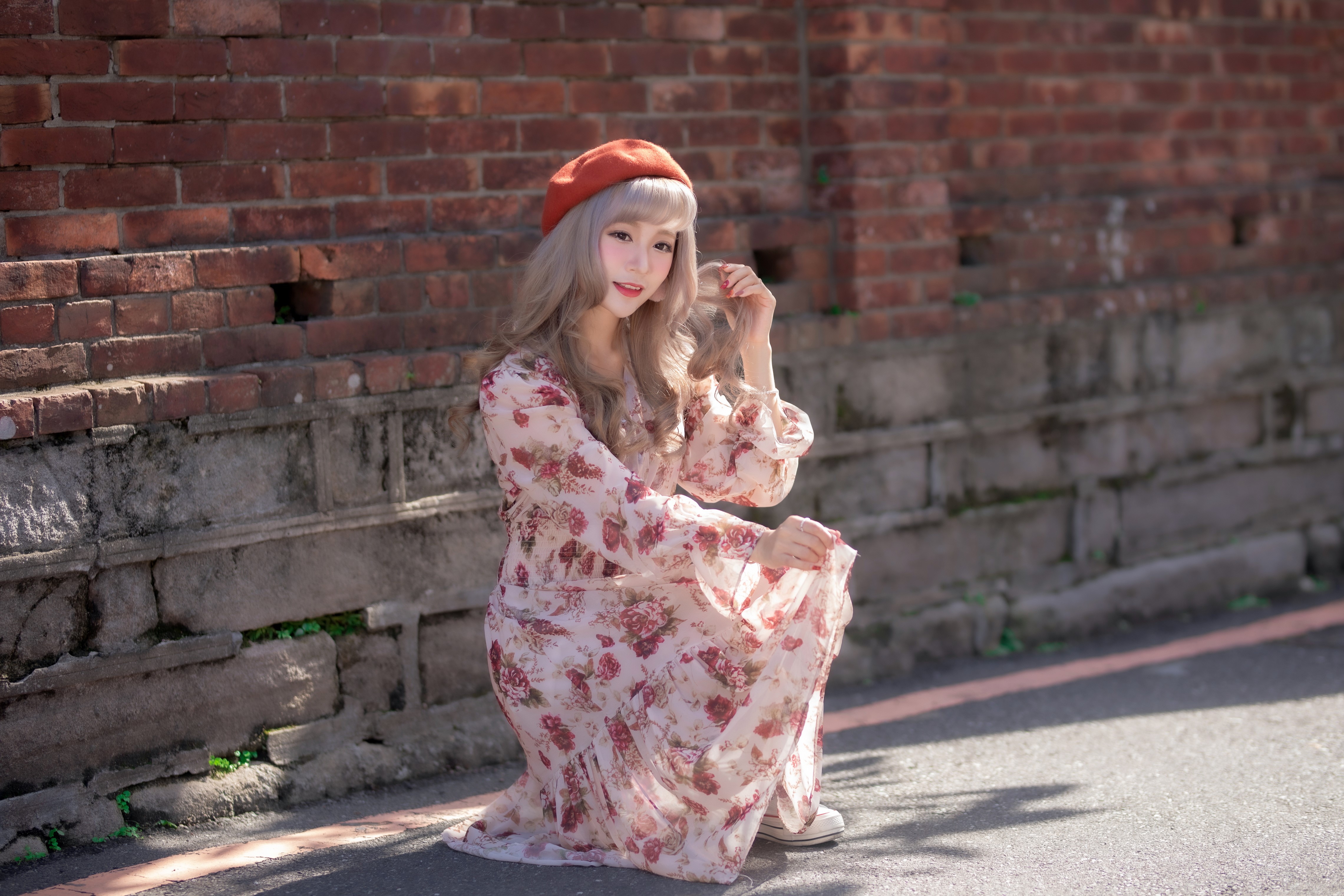 Asian woman in floral dress and beret posing by brick wall HD Wallpaper